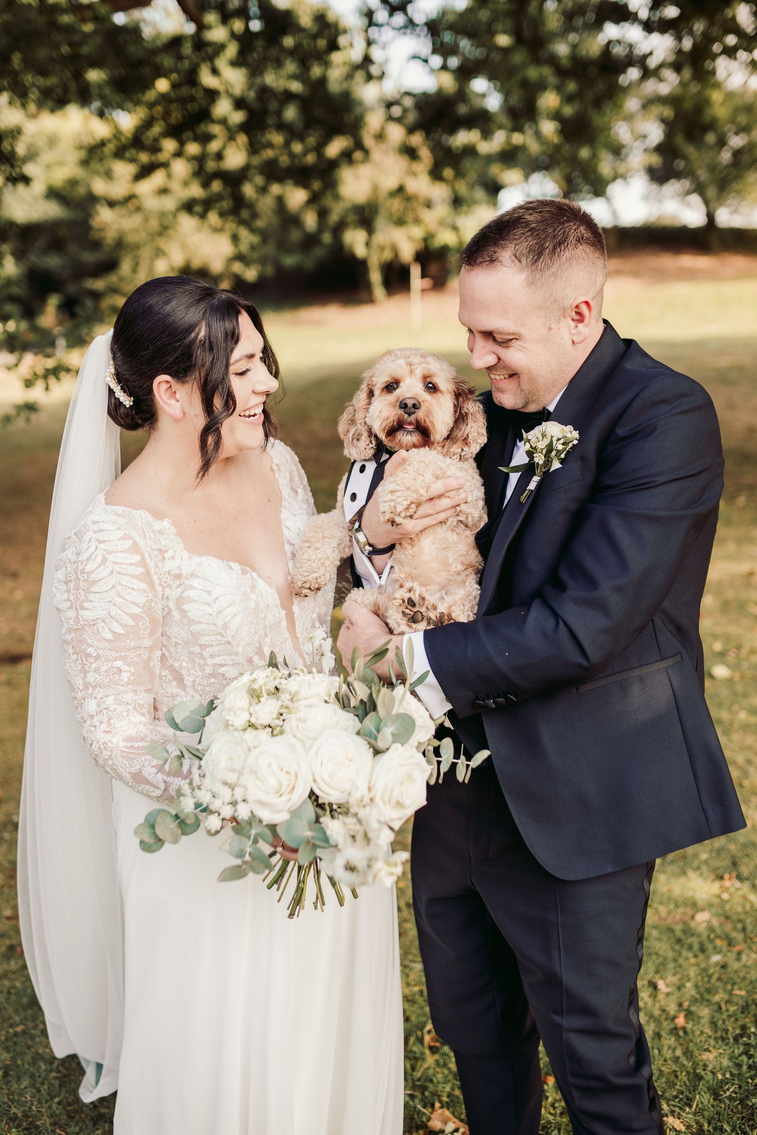 Romantic wedding couple shares intimate moments in a sunny outdoor setting with white floral bouquet.