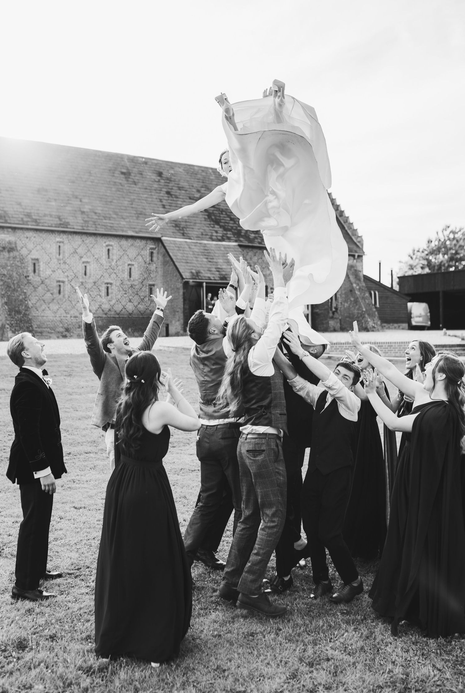 A sequence of black and white photos showing people in dark clothing tossing white sheets into the air outdoors.