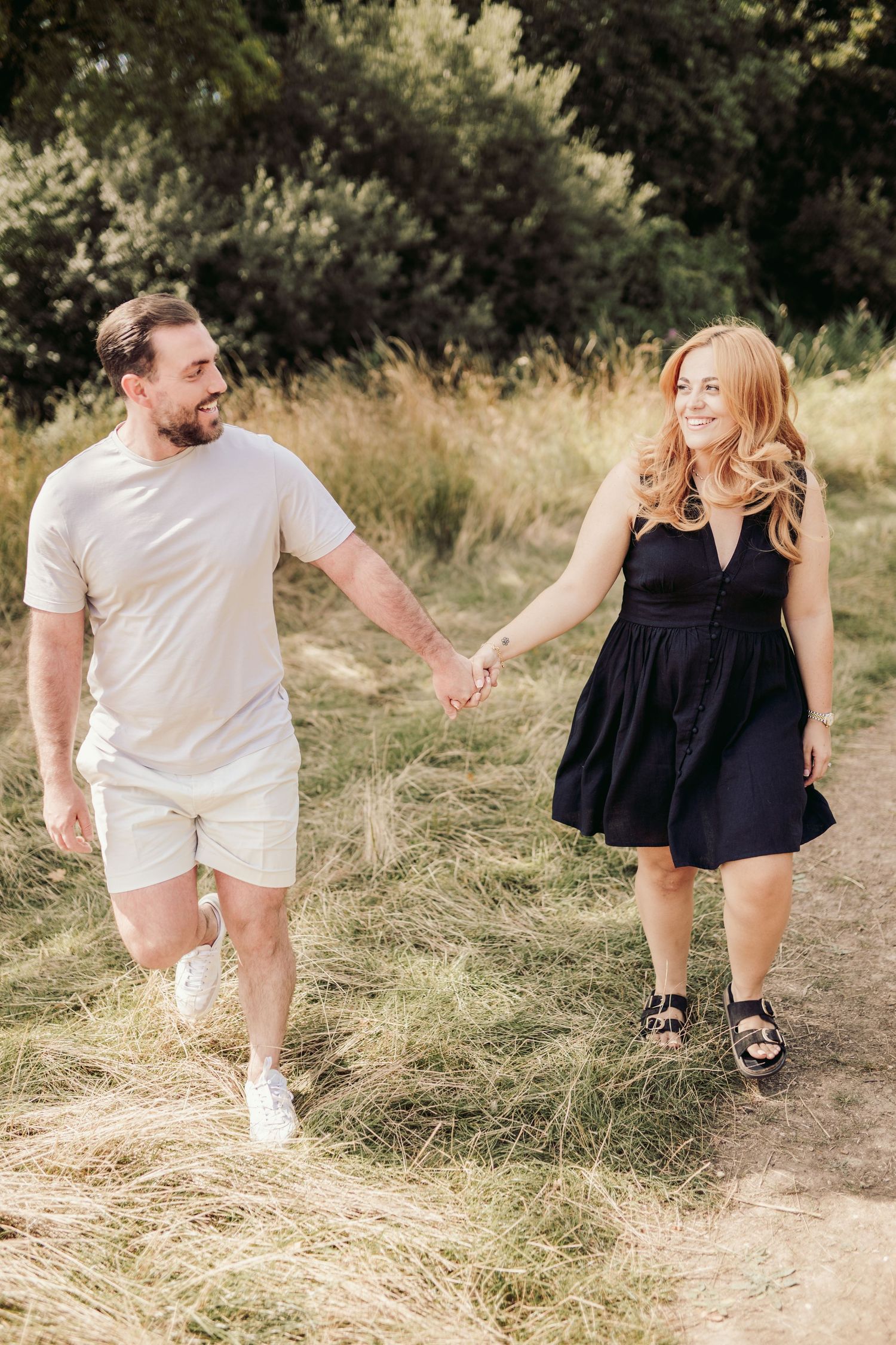 A couple walks hand in hand along a nature trail wearing coordinated summer outfits.