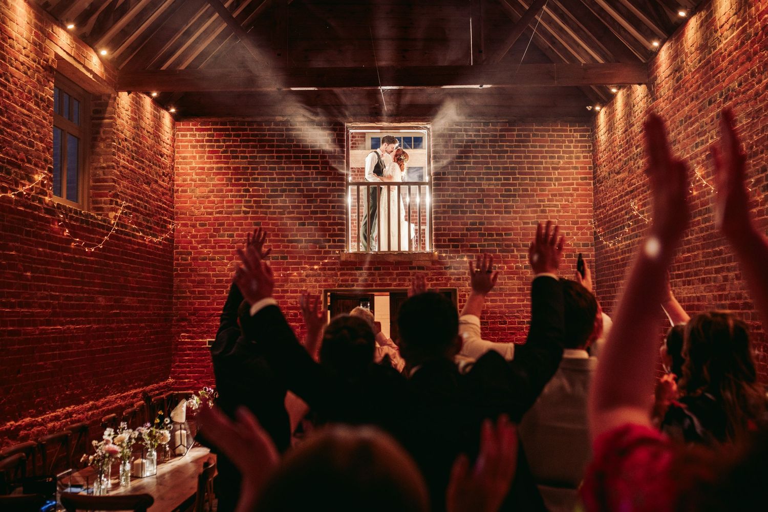 Crowd silhouettes raise hands in celebration under dramatic red lighting.