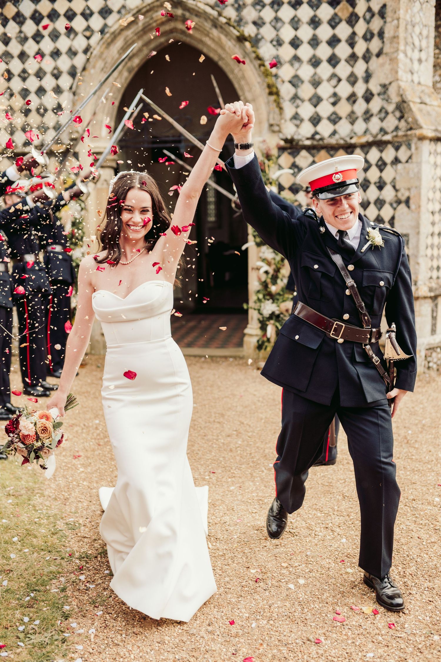 A joyful wedding celebration with rose petals being thrown outside a historic church entrance.