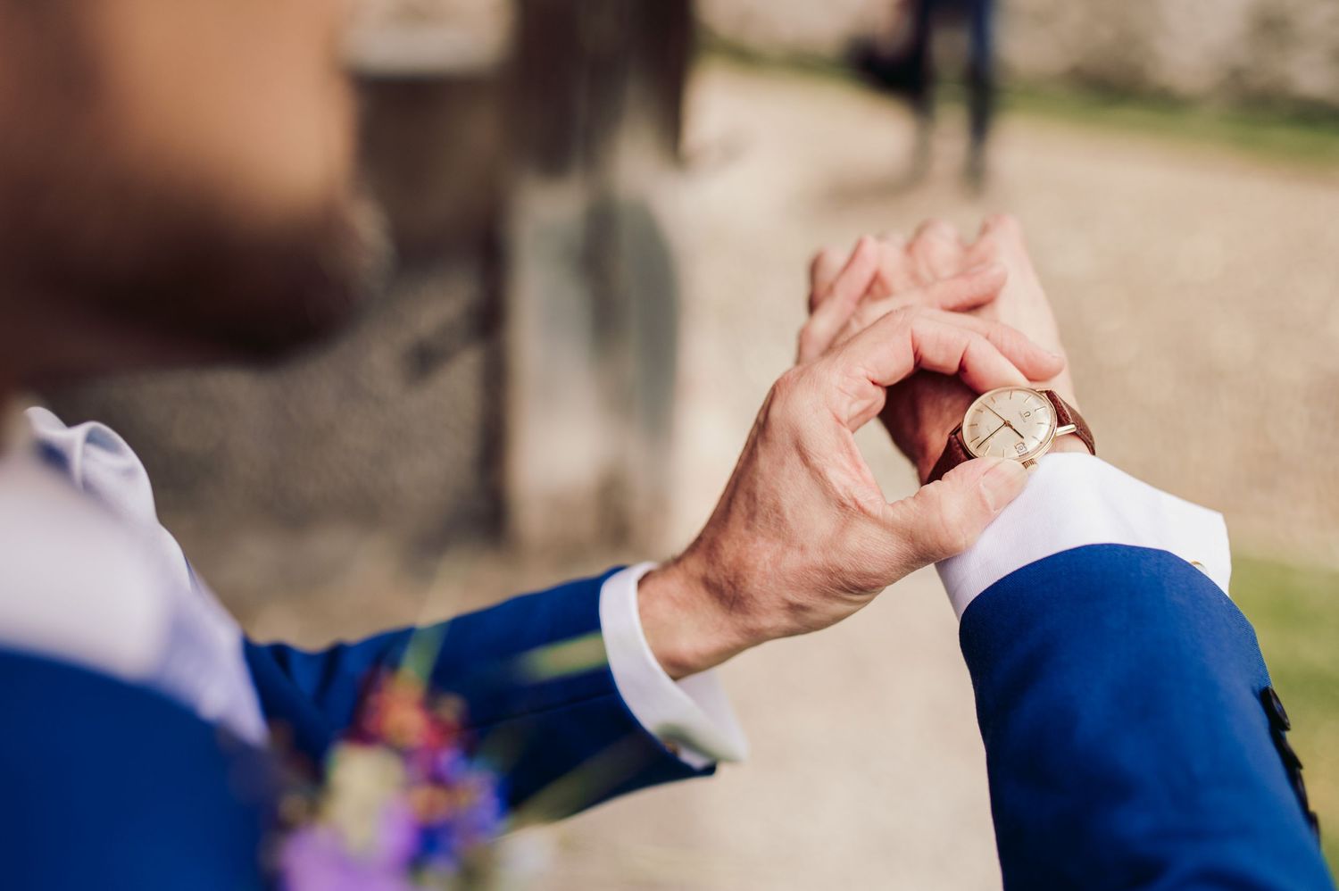 Hands in formal attire check the time on a wristwatch during an outdoor event. Spiez switzerland destination wedding