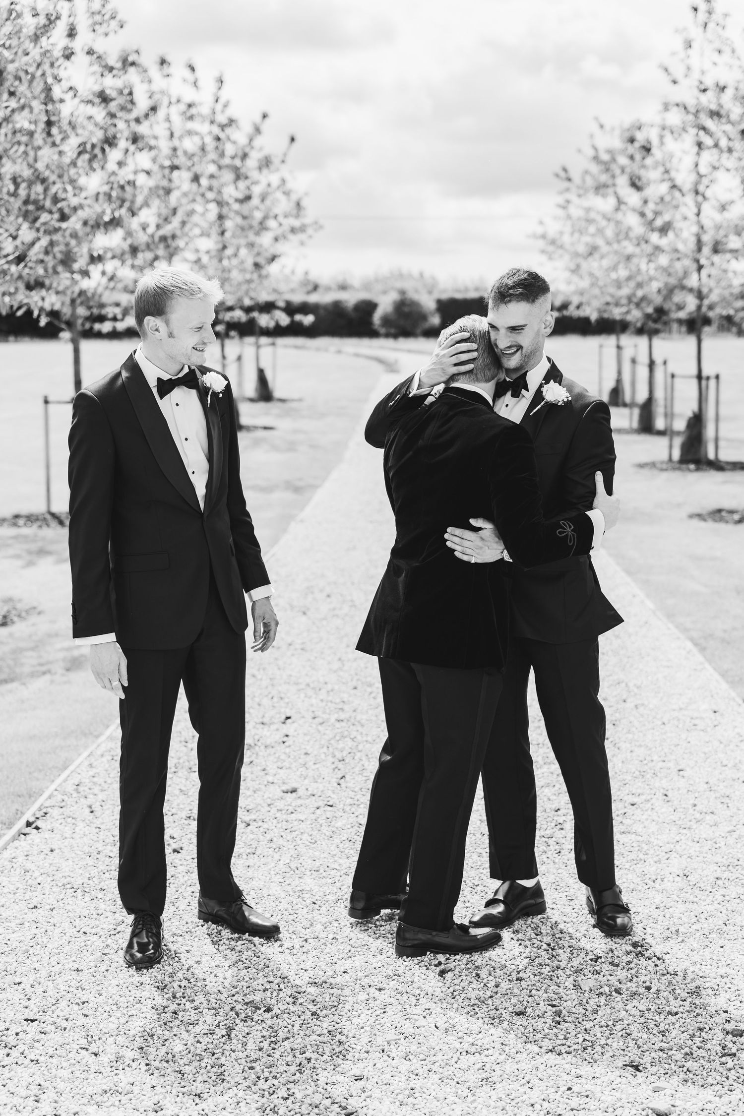Black and white photo series showing people in formal attire playfully interacting outdoors on a gravel path.
