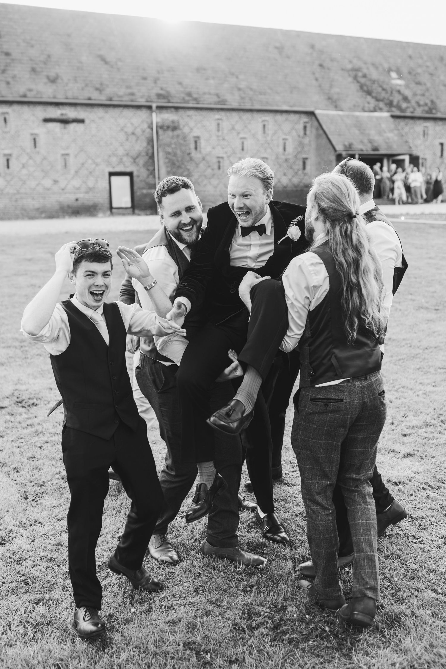 A sequence of vintage black and white photos showing a playful group of people crouching and laughing in a field.