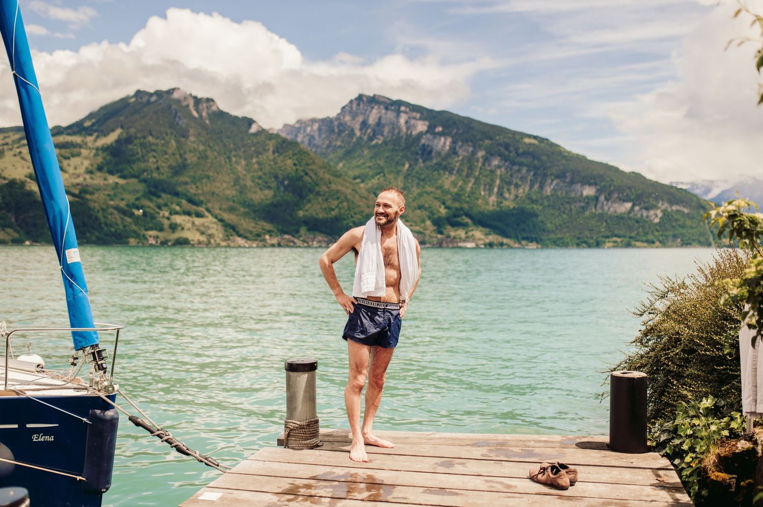 Wooden dock extends into turquoise lake surrounded by majestic mountain peaks on a sunny summer day.Spiez switzerland destination wedding