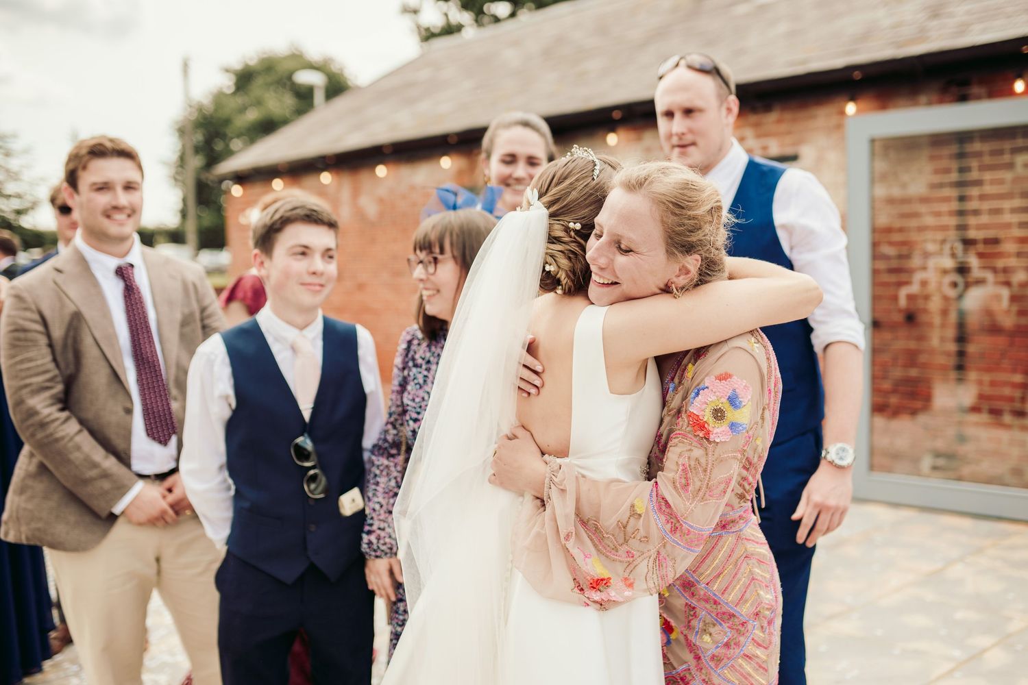 Wedding party laughs and celebrates together during outdoor reception at rustic brick venue.