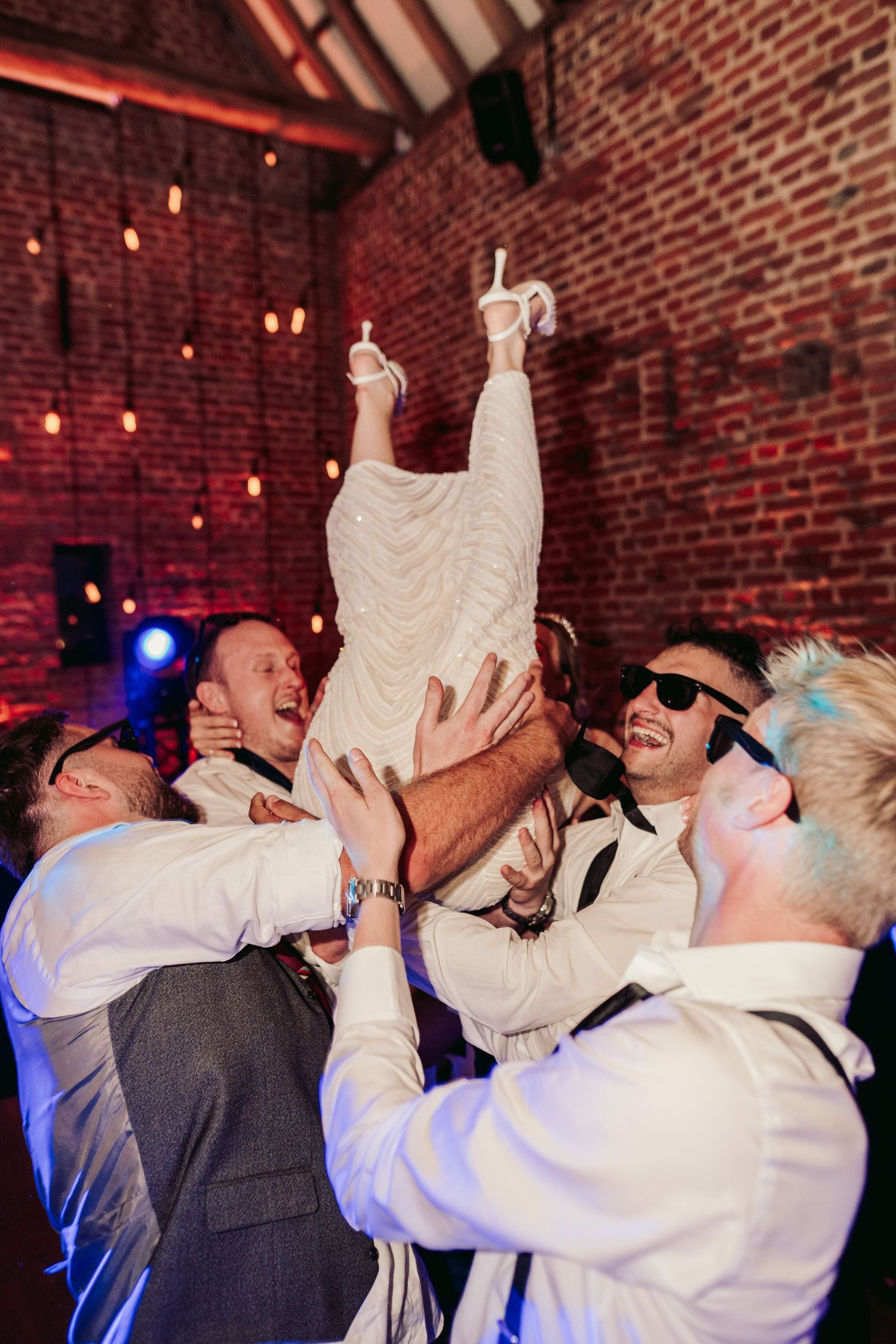 Sequence of party guests taking shots at a wedding reception in a rustic brick venue with mood lighting.