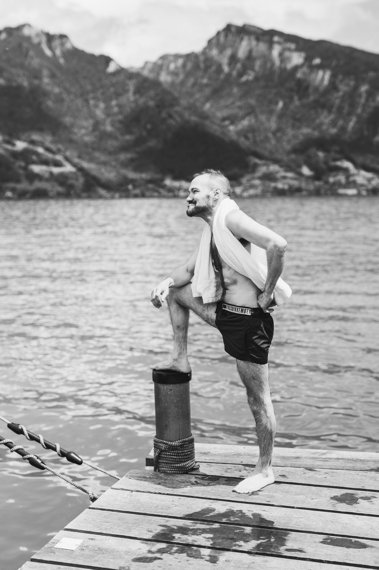 A vintage black and white photo shows a swimmer standing on a wooden pier overlooking a mountain lake.Spiez switzerland destination wedding