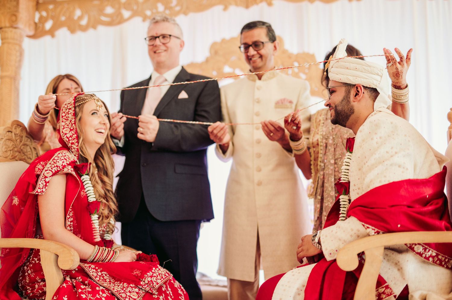 Traditional Indian wedding ceremony with couple in red attire sharing a joyful moment during rituals.
