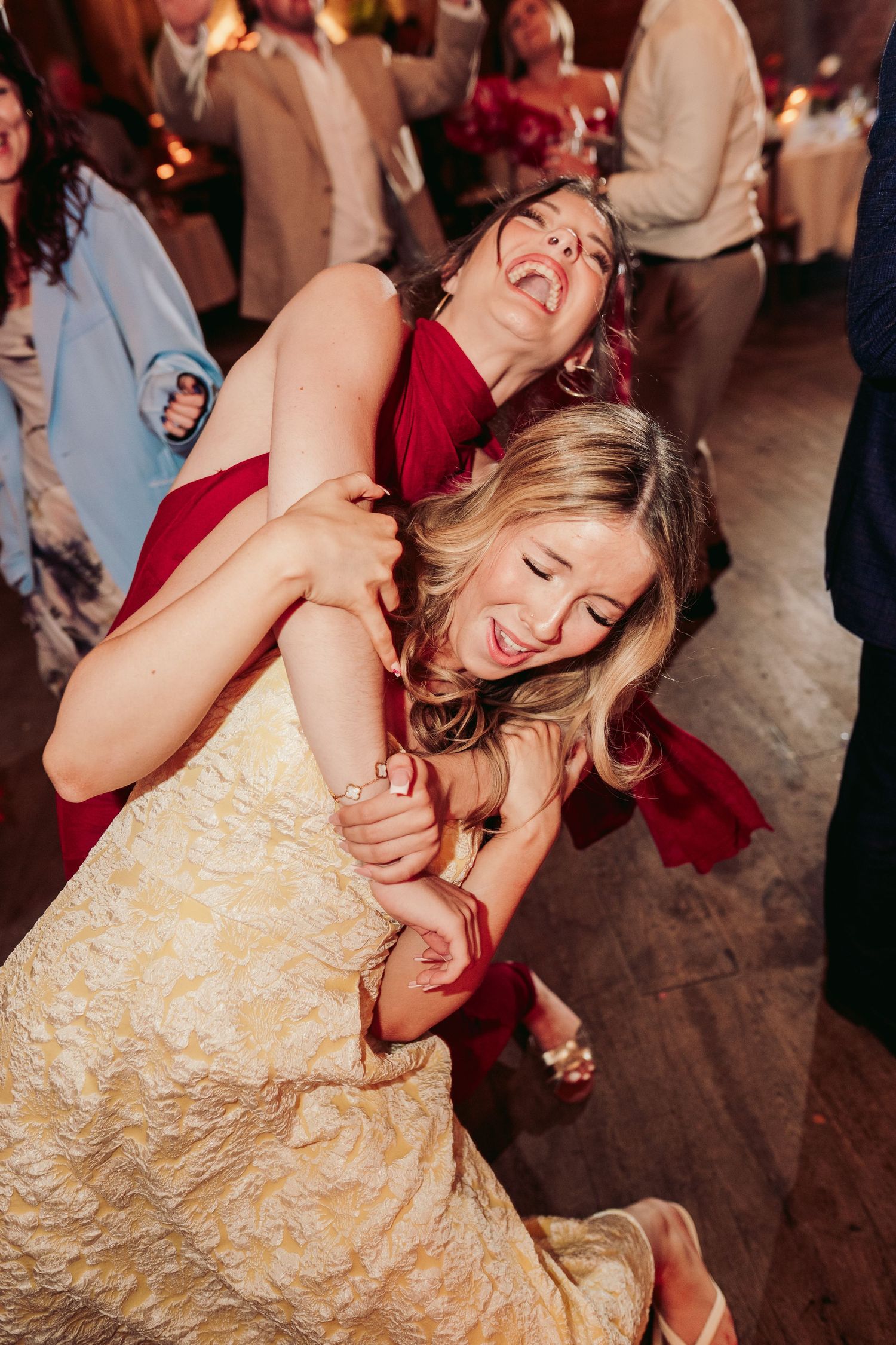 Wedding guests dancing joyfully at a reception with warm lighting and festive atmosphere.