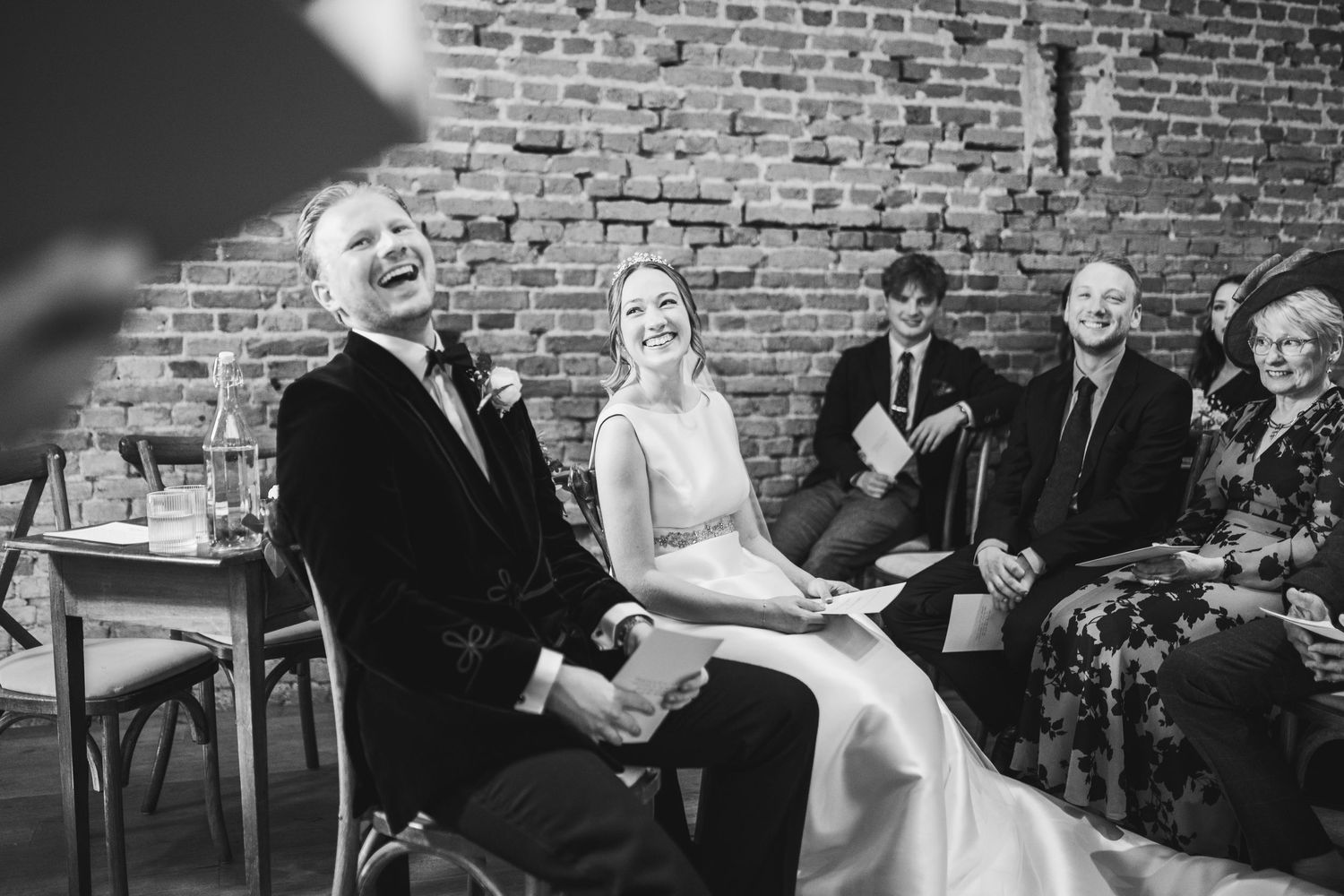 Wedding guests enjoy dancing and celebrating on the dance floor at a rustic brick-walled reception venue.