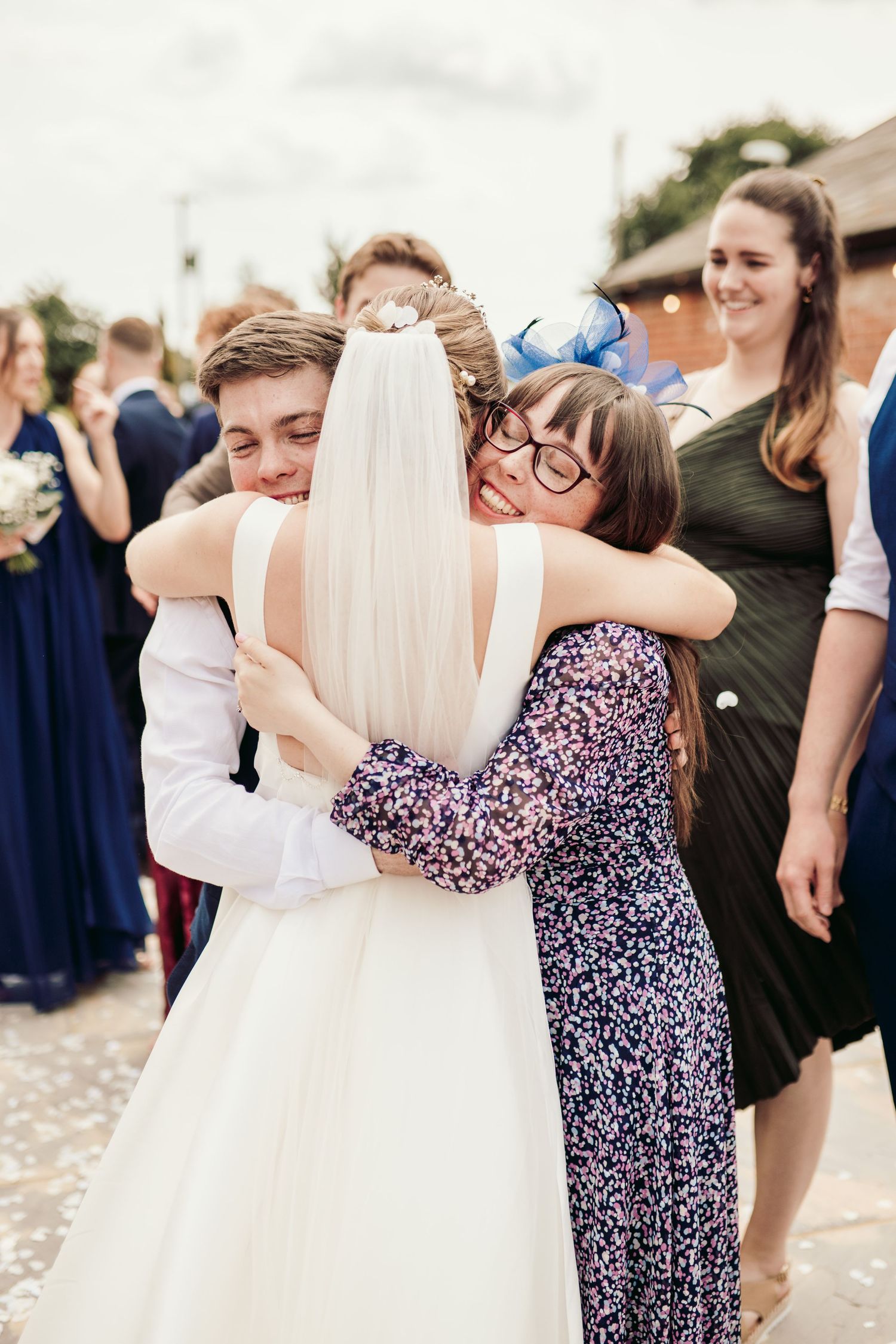 Wedding guests share warm embraces with the bride in her white gown during an outdoor celebration.