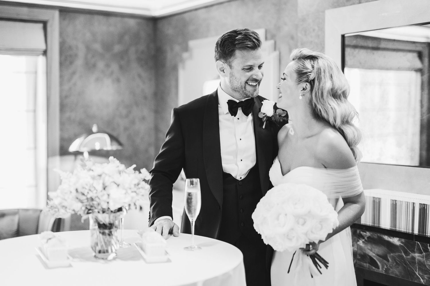 A couple shares a joyful moment together at their wedding reception in black and white photography.Claridge’s wedding