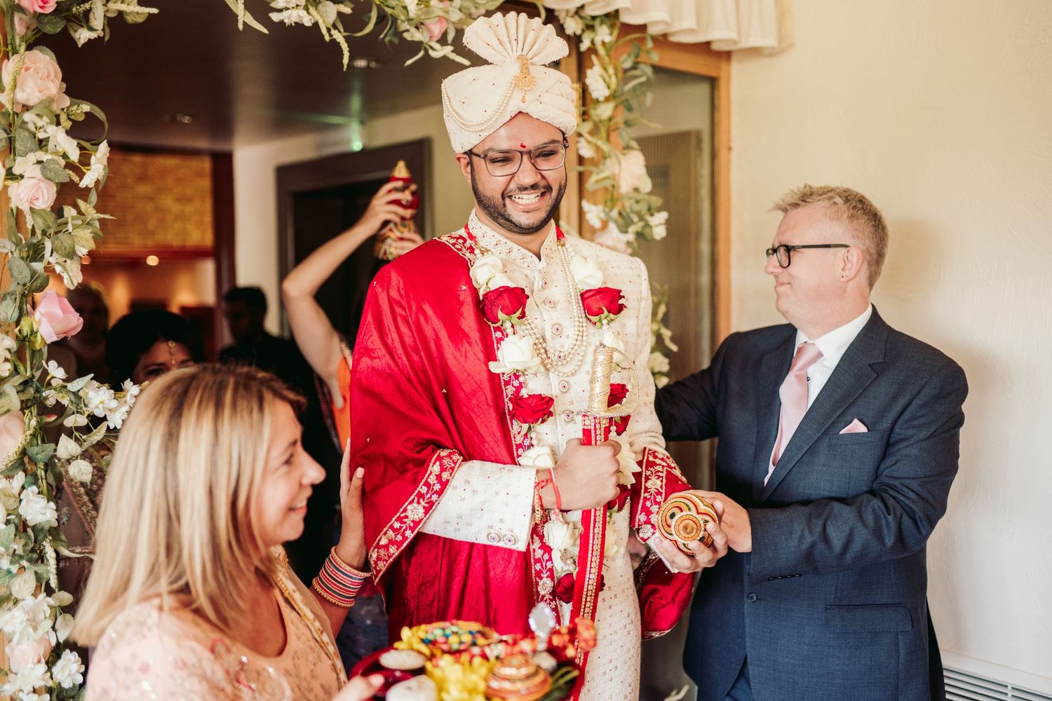 Traditional Indian wedding ceremony with guests in formal attire gathered around colorful cultural decorations and rituals.