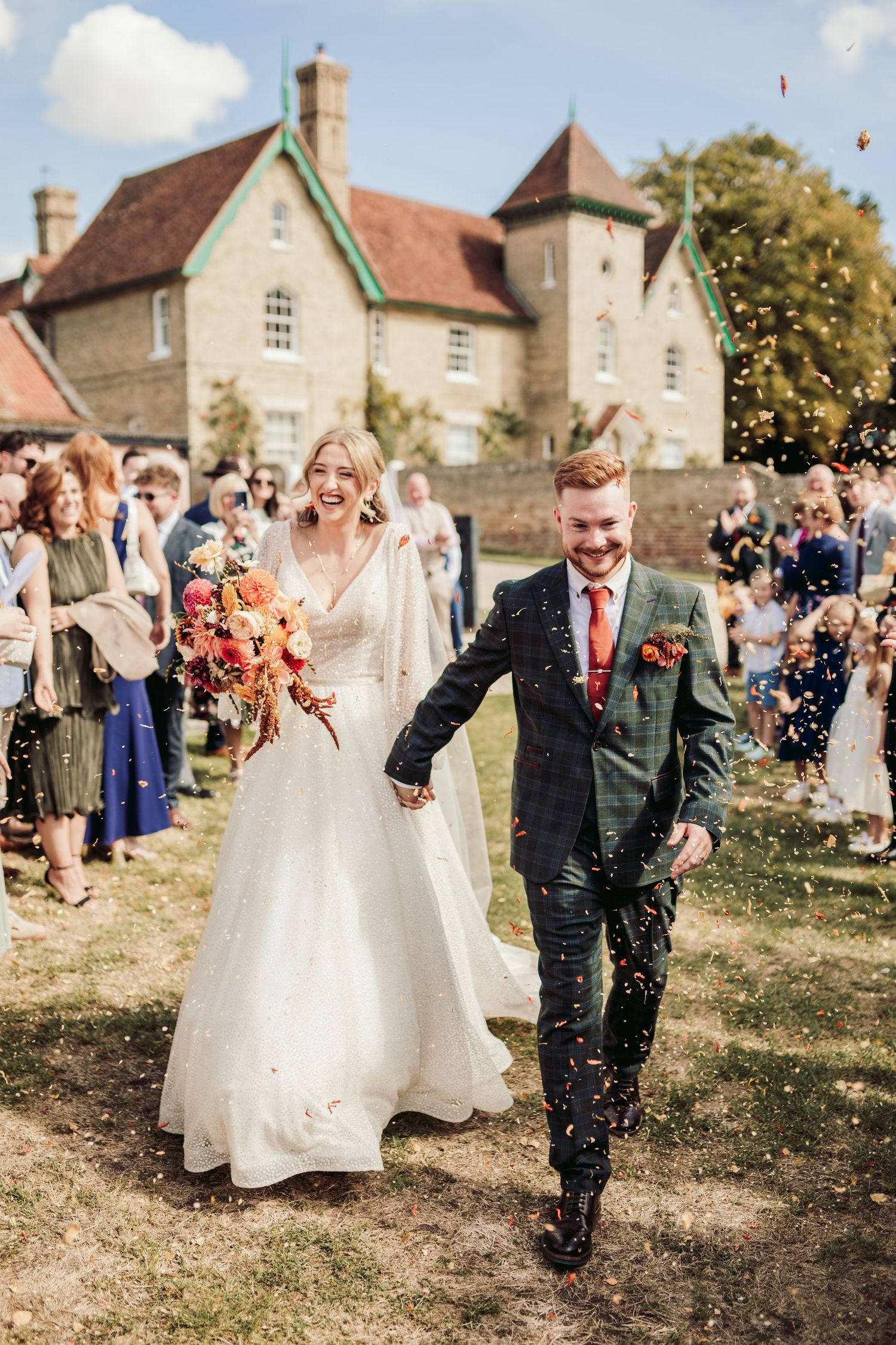 Wedding celebration with confetti toss outside historic stone buildings.