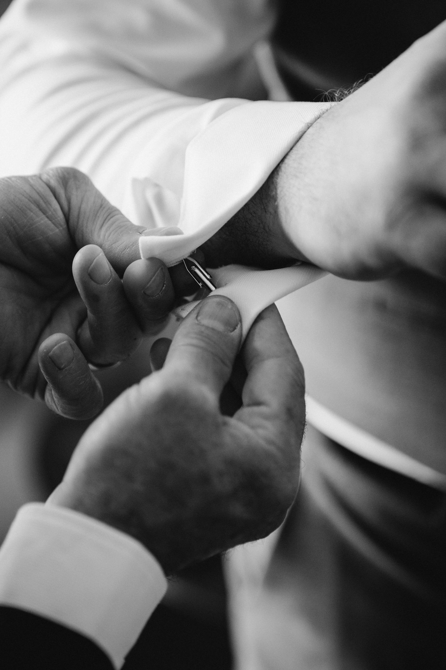 Details of a father fastening is son's cuff-links before his wedding day in the Horseshoe Valley.