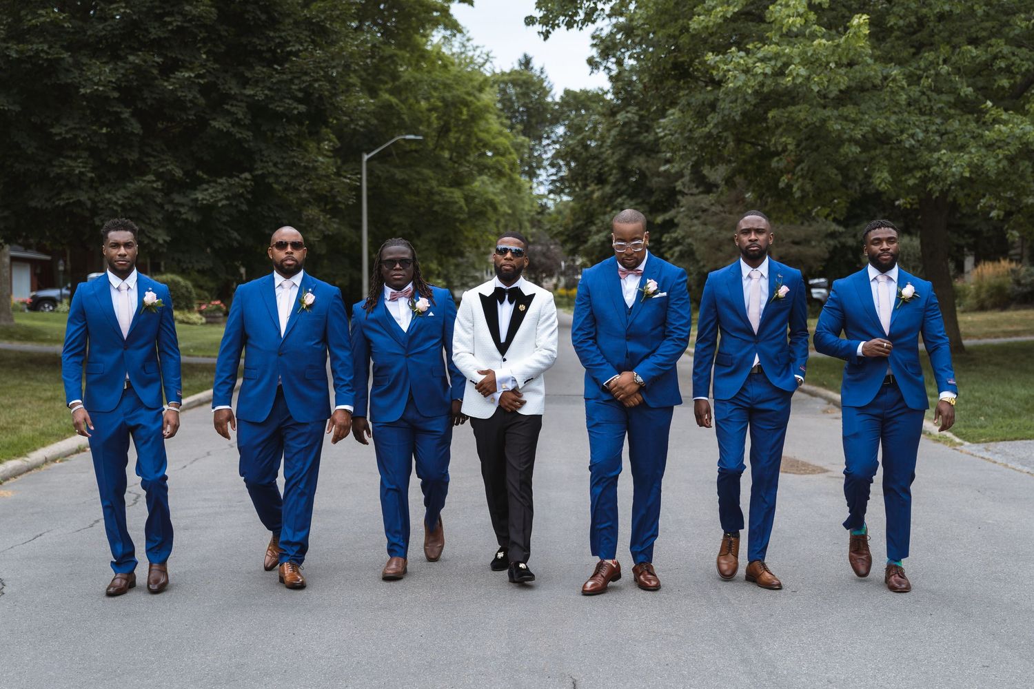 Ottawa wedding, Groom in a white tuxedo is flanked by his groomsmen in contrasting cobalt blue suits.