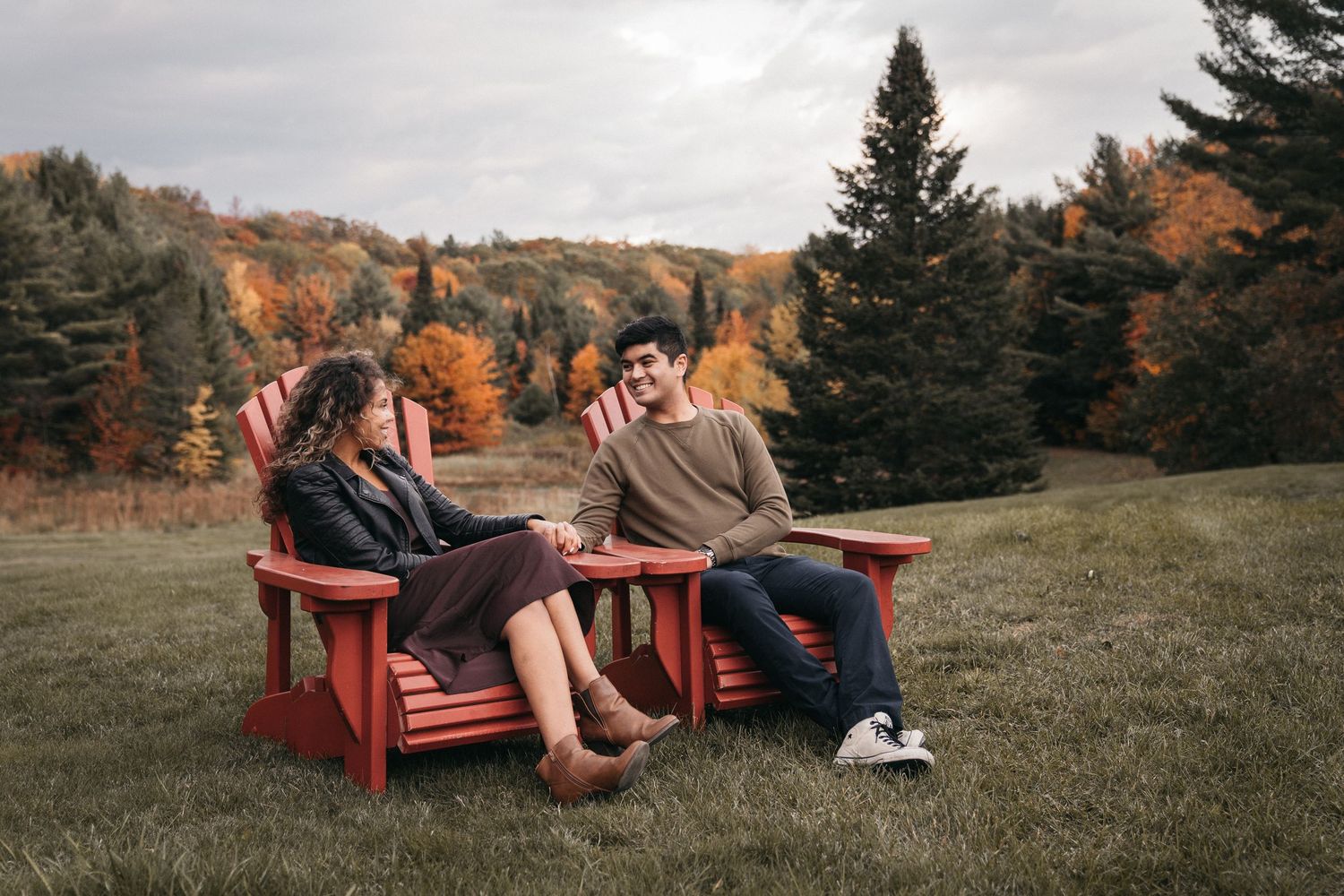 Muskoka outdoor engagement session with couple enjoying a conversation with breathtaking fall colours in the background.