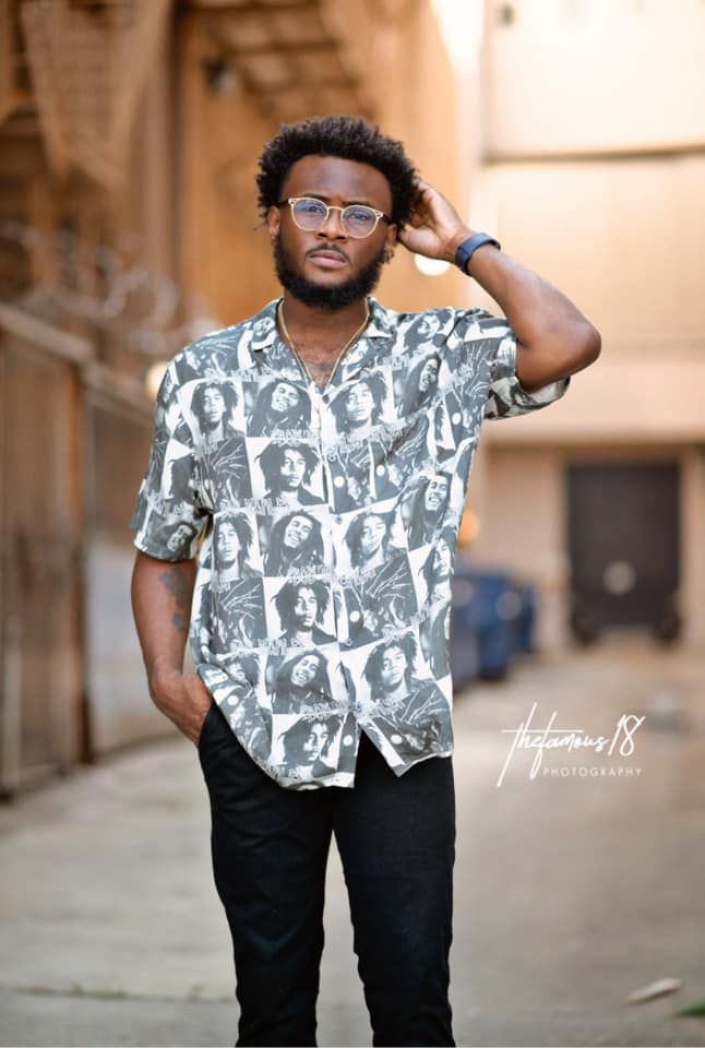 Stylish young man in Bob Marley print shirt posing in an urban alley setting.