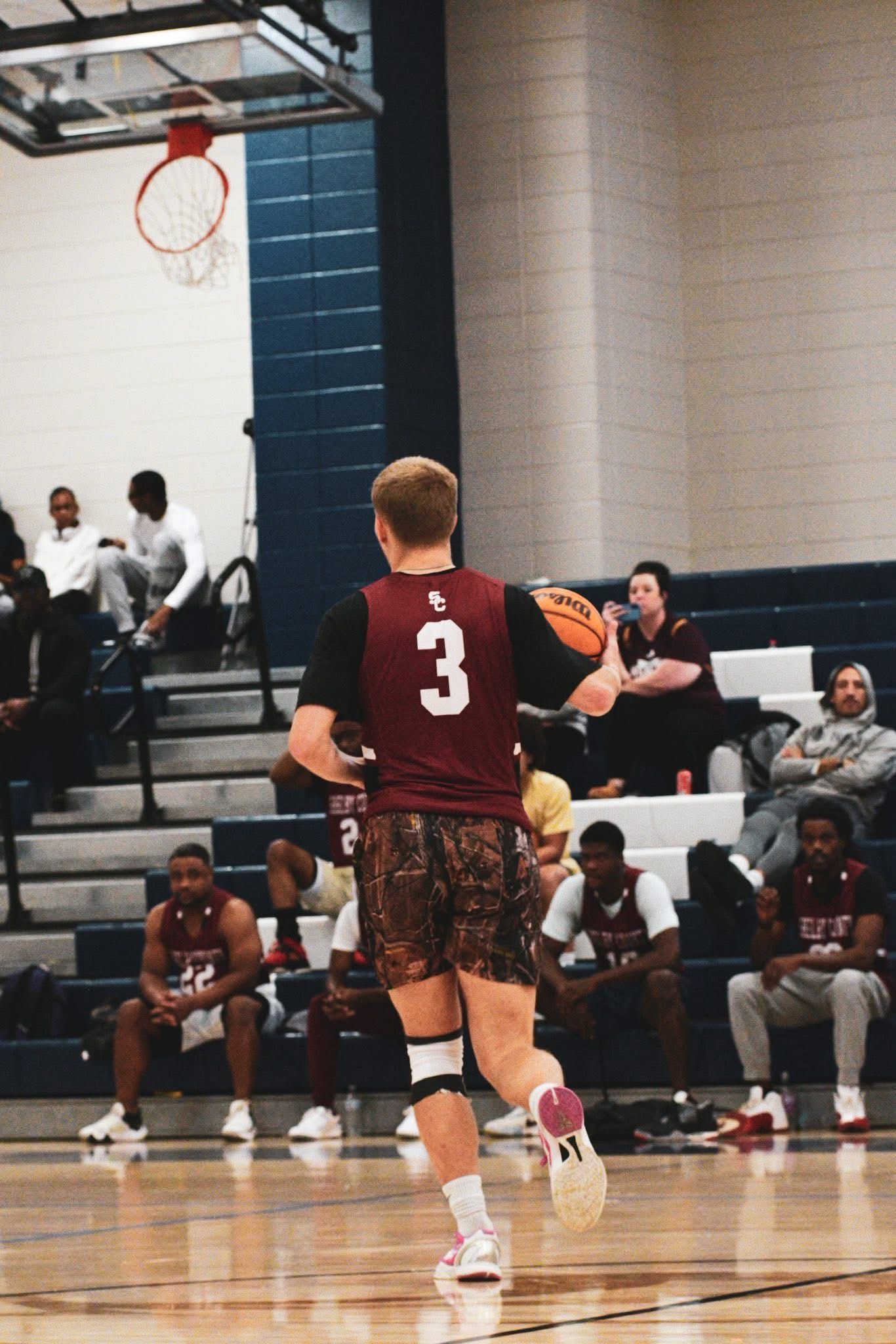 A basketball player wearing jersey number 3 dribbles the ball down the court during an indoor game.
