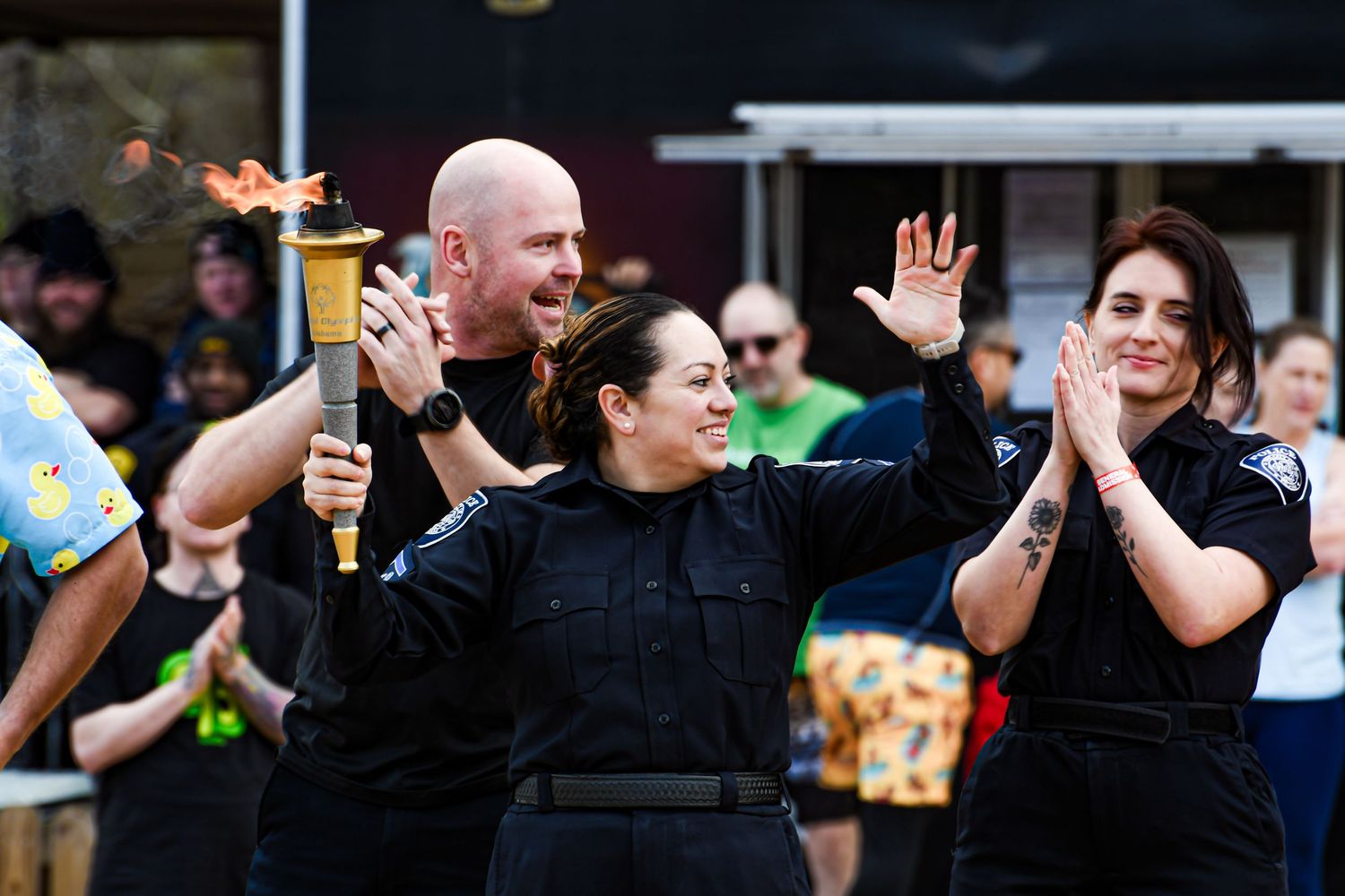 Police officers celebrating outdoors with a lit torch at a public event.