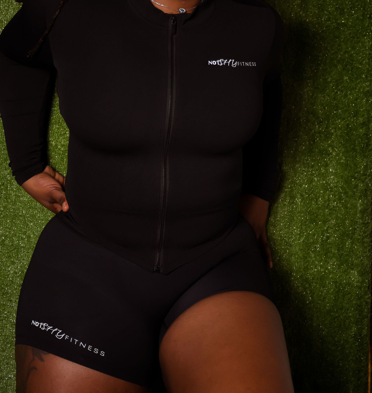 Close-up of a black zip-up athletic romper with NotMyFitness branding on shorts and chest.