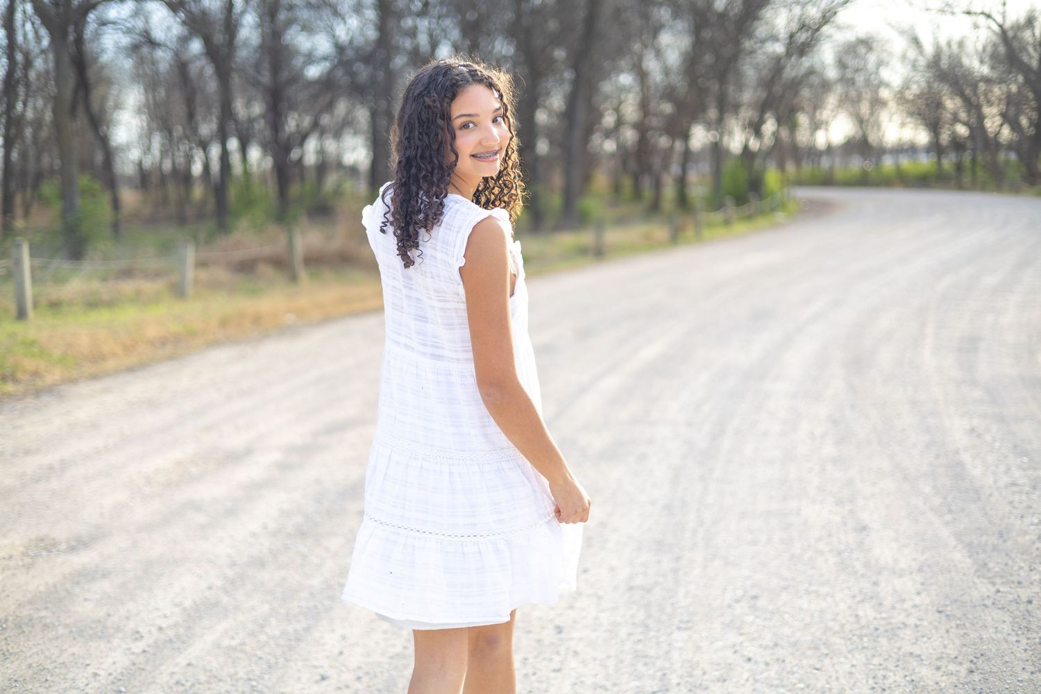 A series of six photos shows someone in a white dress walking along a rural dirt road on a sunny day.