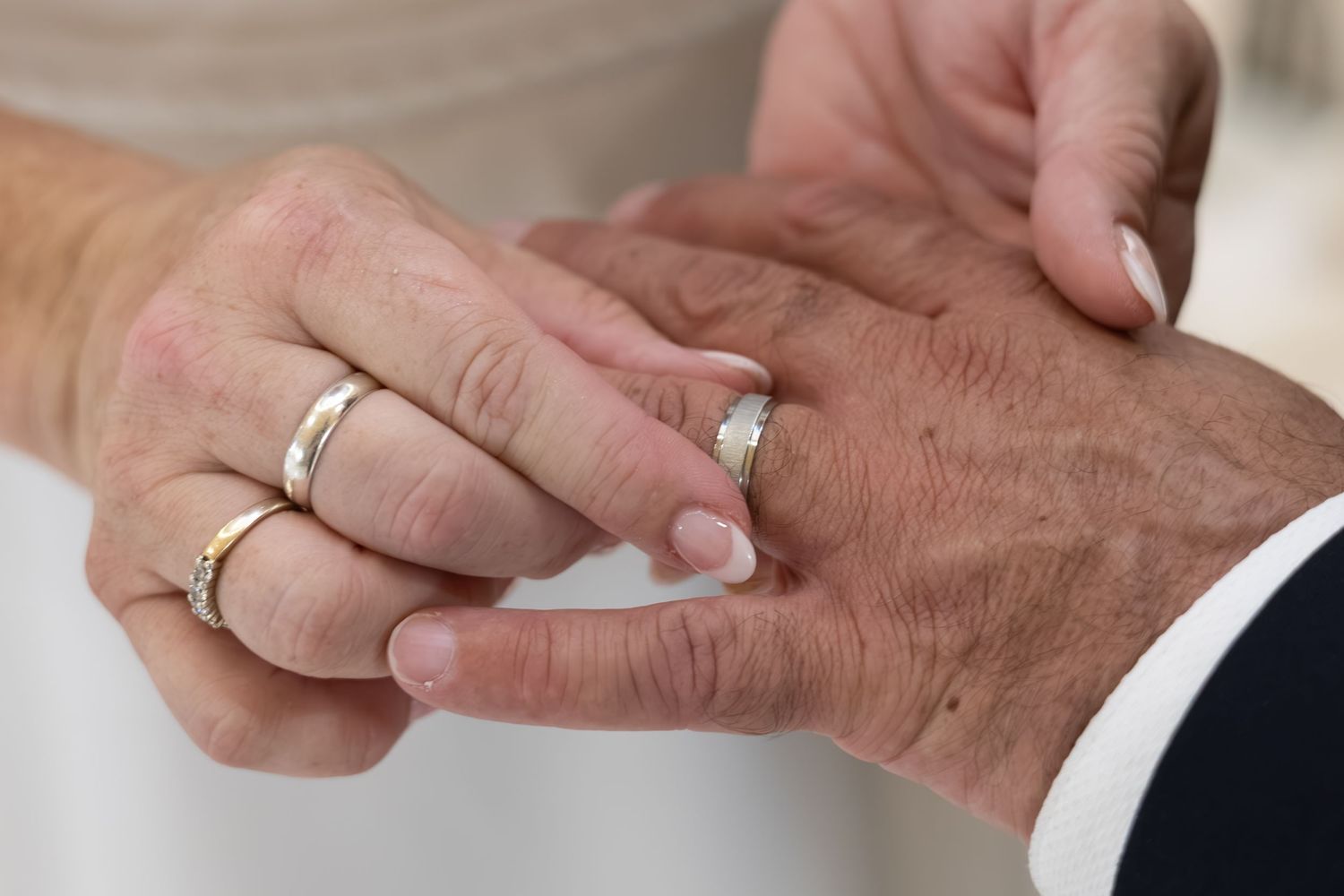 Close-up of elderly couple exchanging wedding rings during marriage ceremony, symbolizing love and commitment.