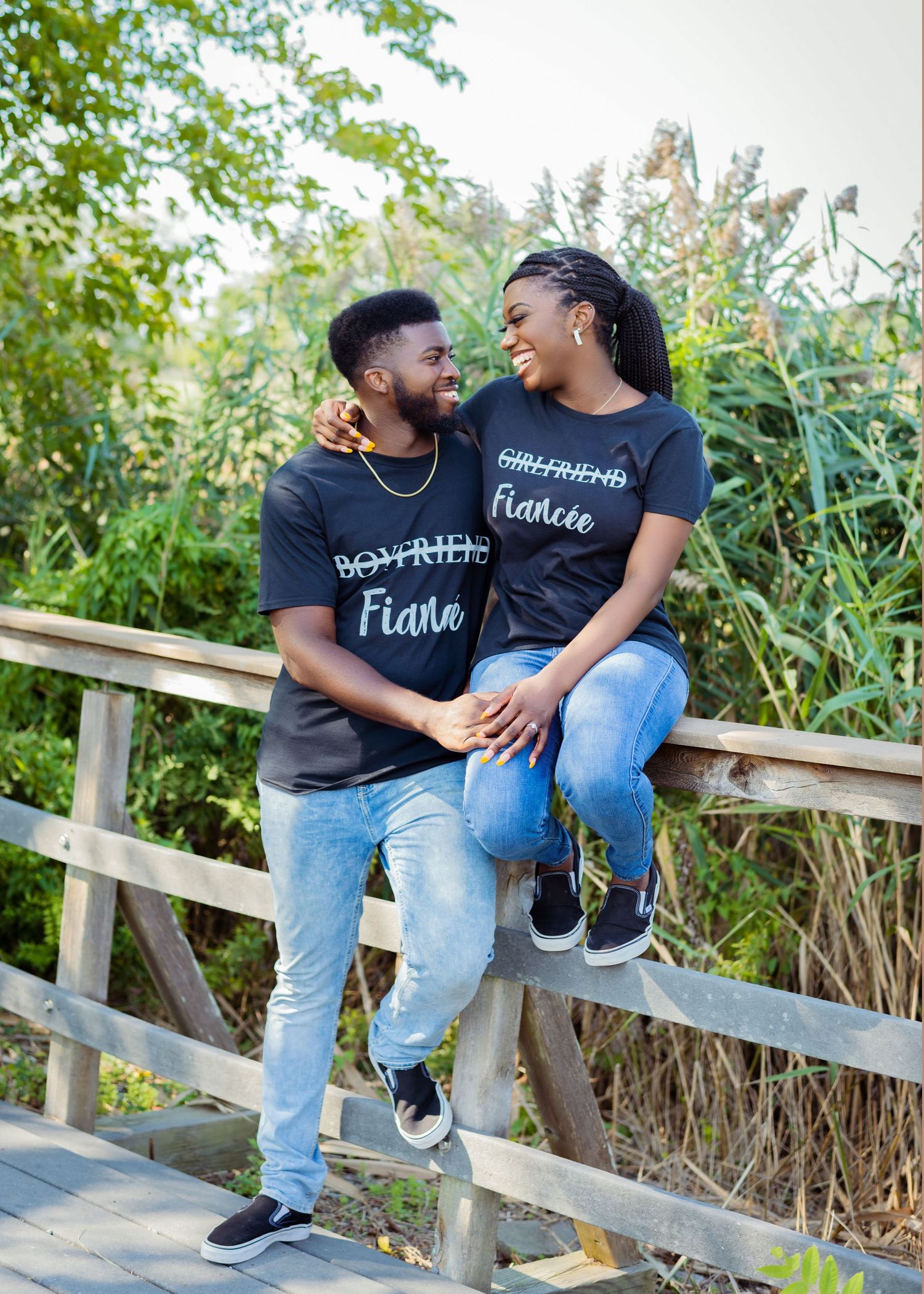 Couple in matching t-shirts sitting on wooden fence sharing intimate moments.
