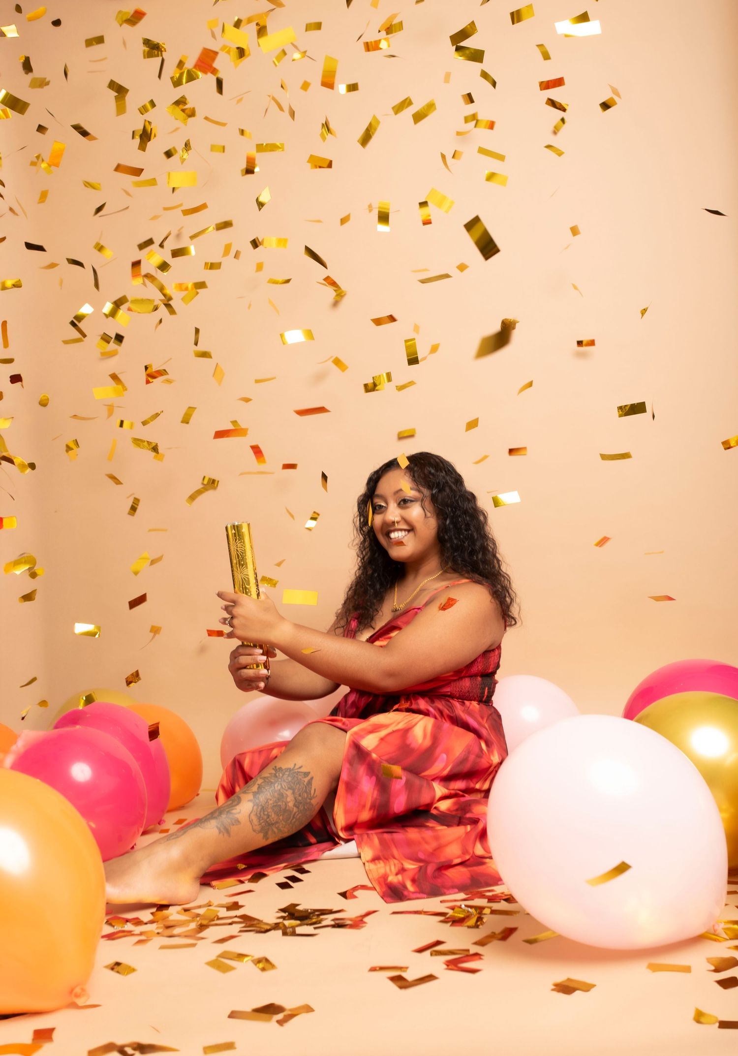 Festive scene with gold confetti falling and colorful balloons against a peach background.