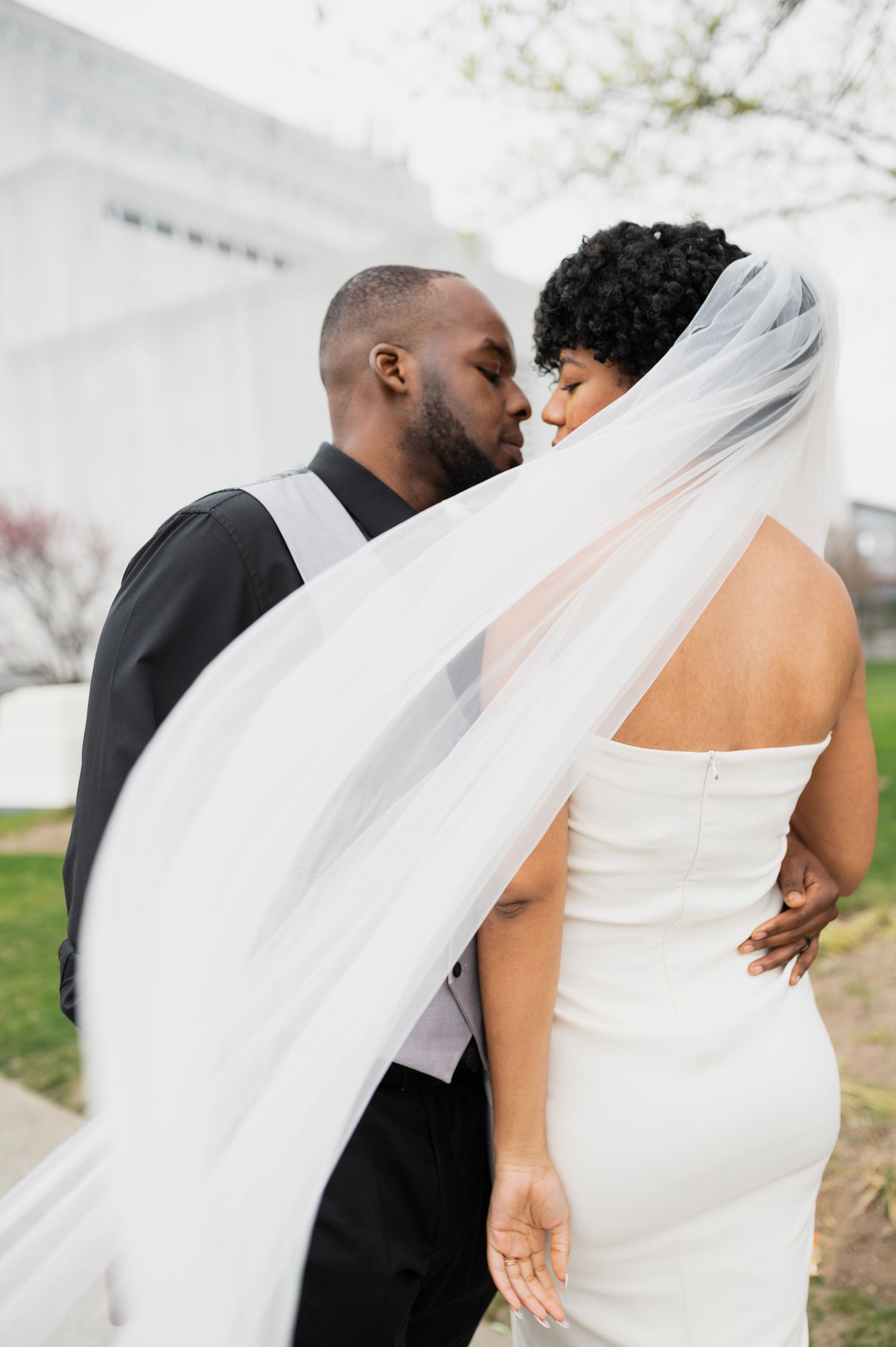 Romantic wedding photos with flowing white veil against spring blossoms.