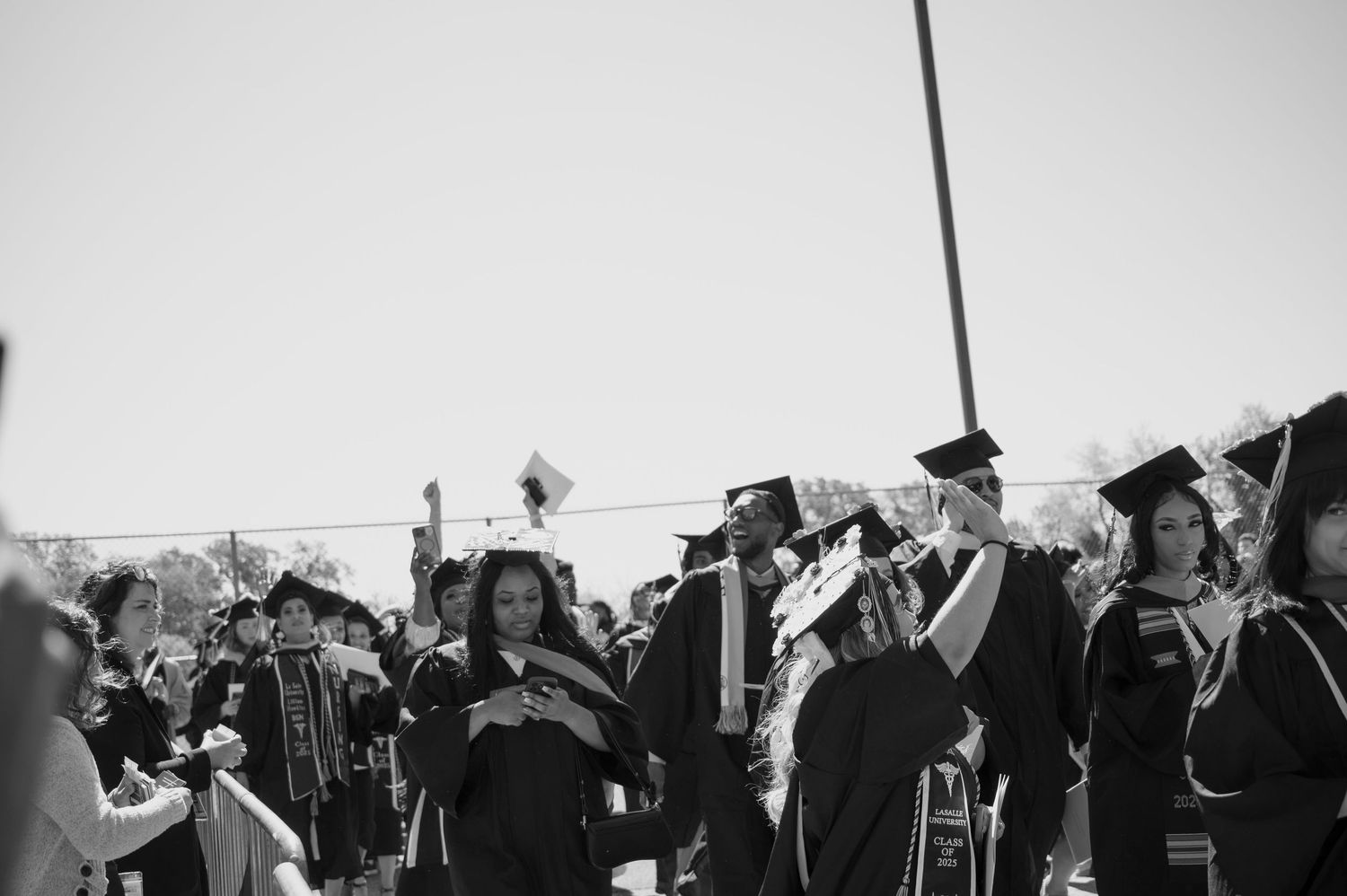 Black and white photo of a crowd gathered outdoors with raised hands during a celebration.