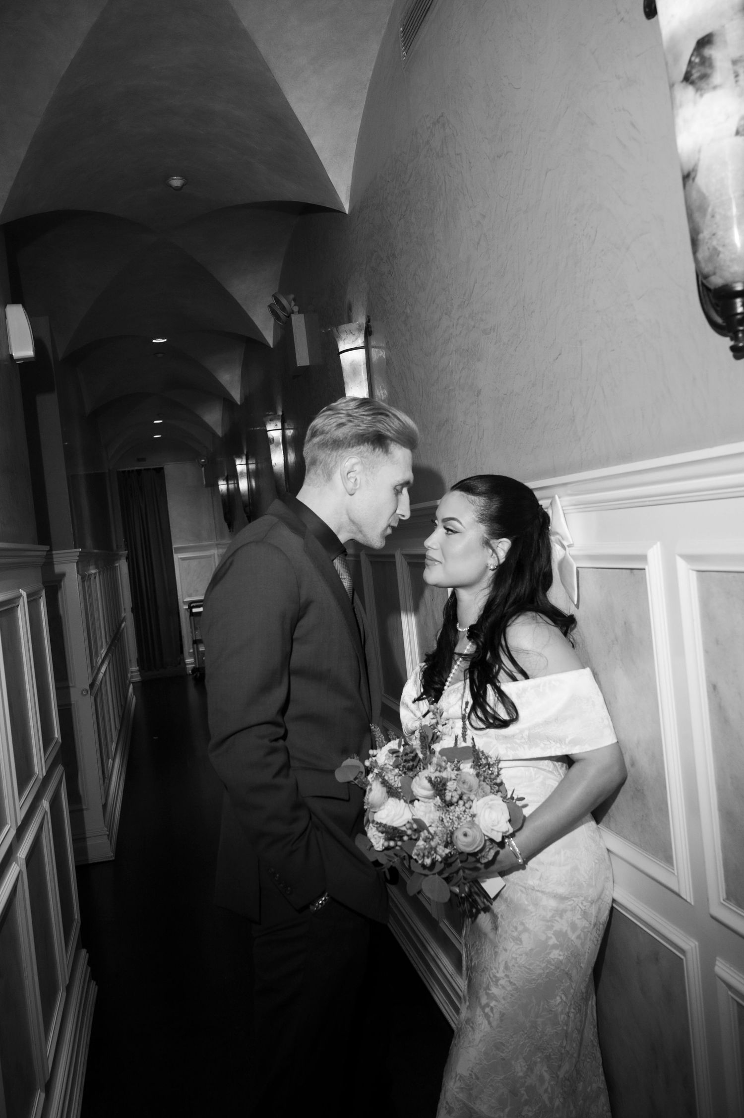 A romantic moment captured in a hallway with elegant white wainscoting.