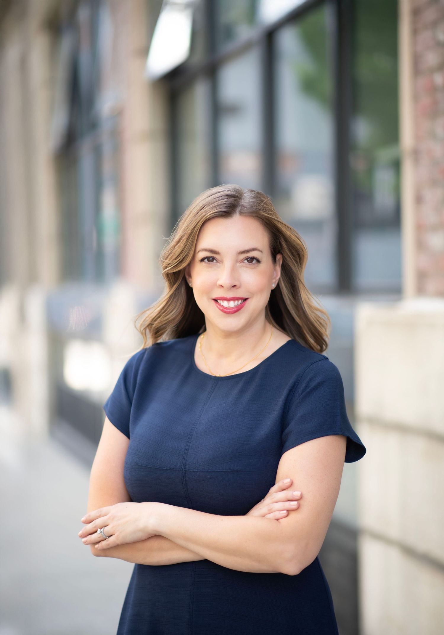 Professional business portraits of someone in a navy dress against an urban backdrop.