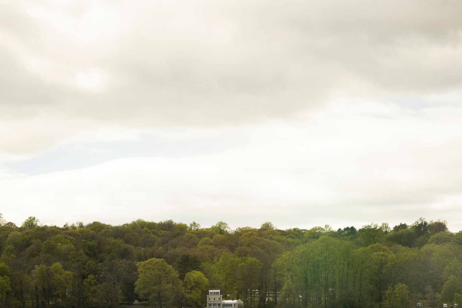 Panoramic nature scene showing wooded hills and cloudy sky at sunset.