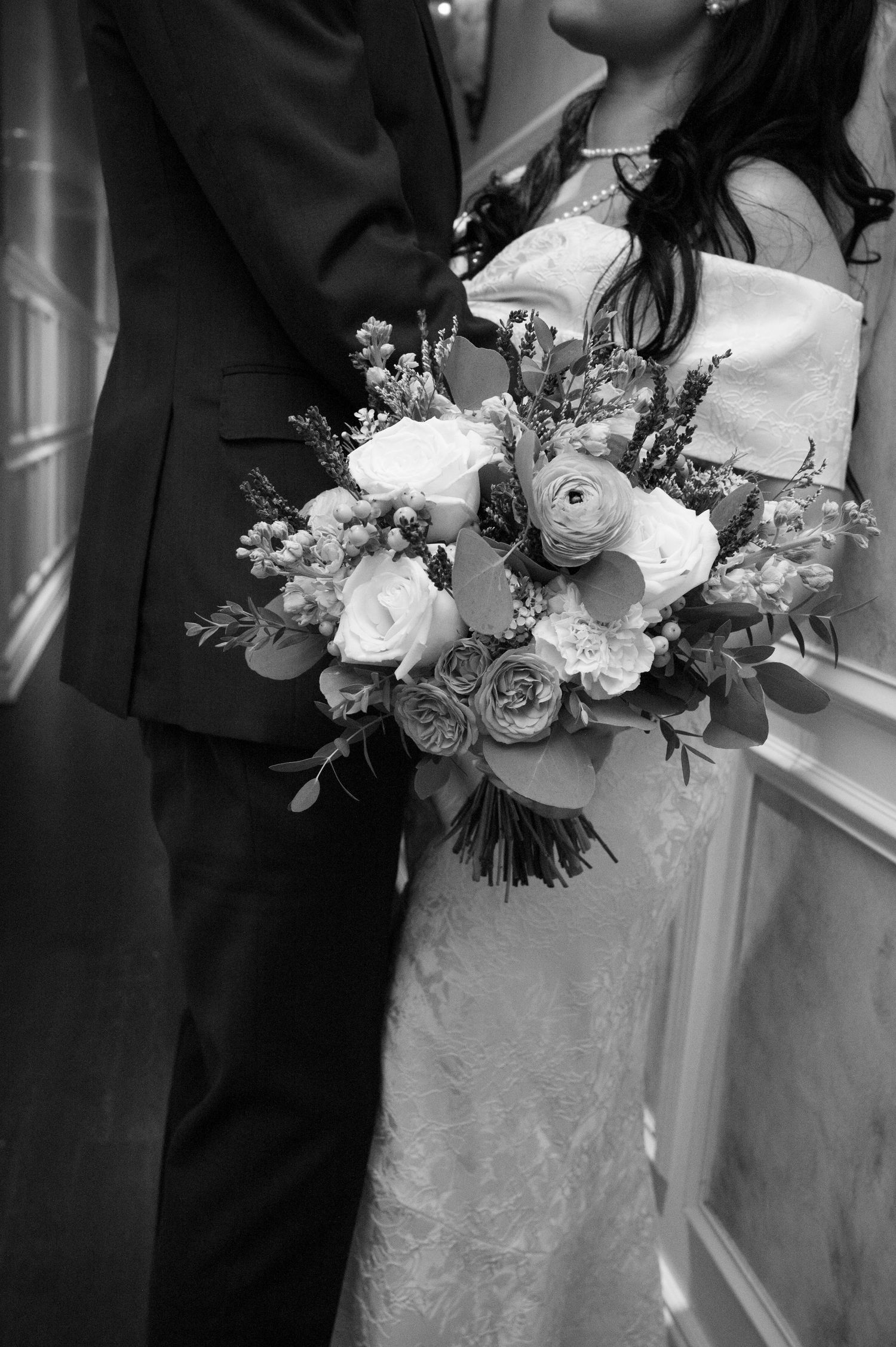 A couple embraces while holding a beautiful white floral bouquet.