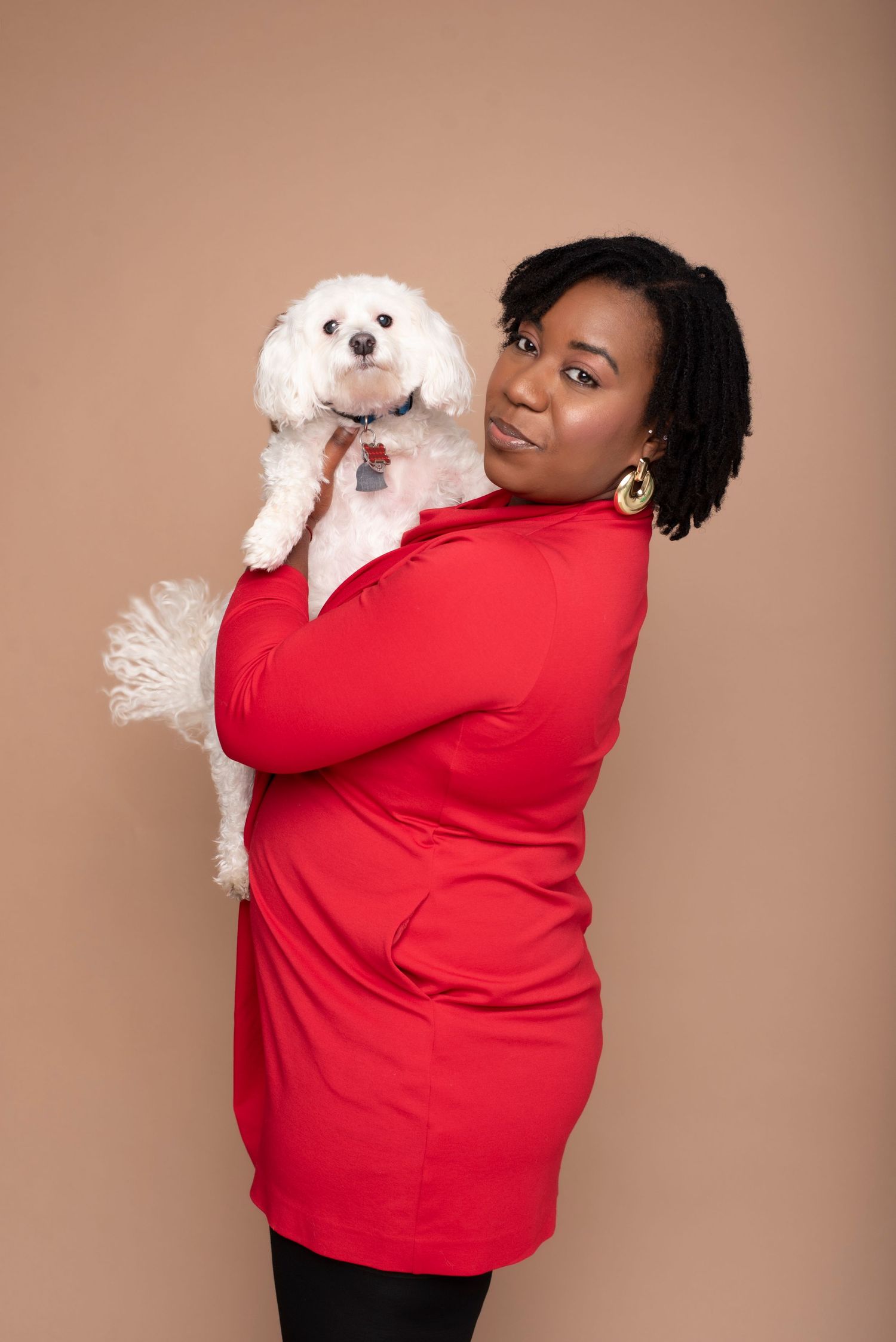 Woman in red top posing with a white Bichon Frise dog over her shoulder in a studio setting.