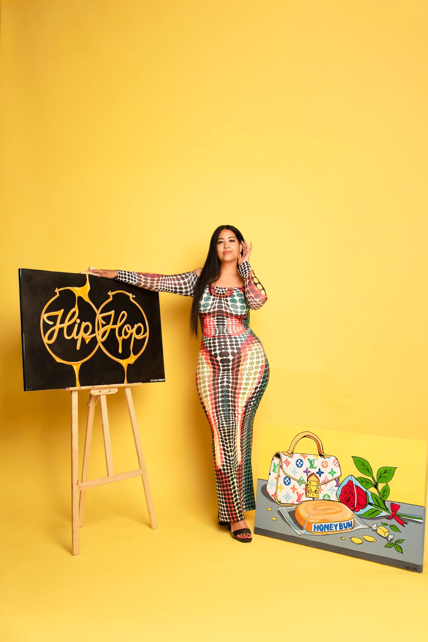 Creative yellow backdrop photo series with wooden chairs and decorative props. Artist standing with paintings.