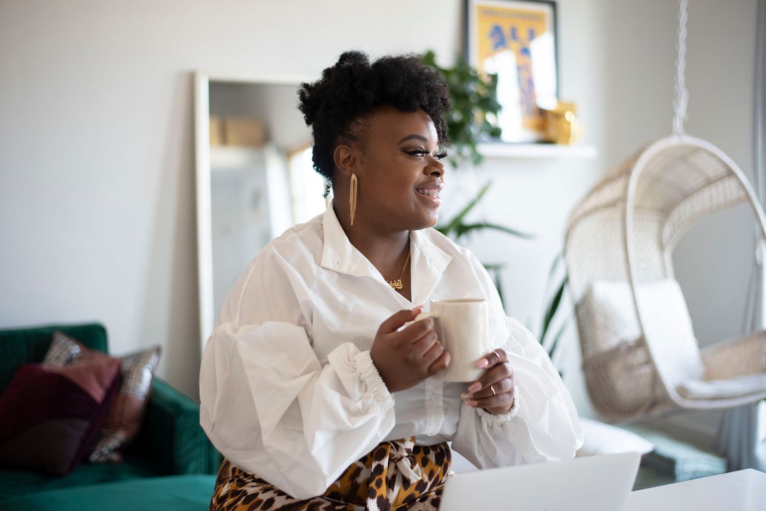 Person in white attire sitting comfortably while reading and enjoying a hot beverage.