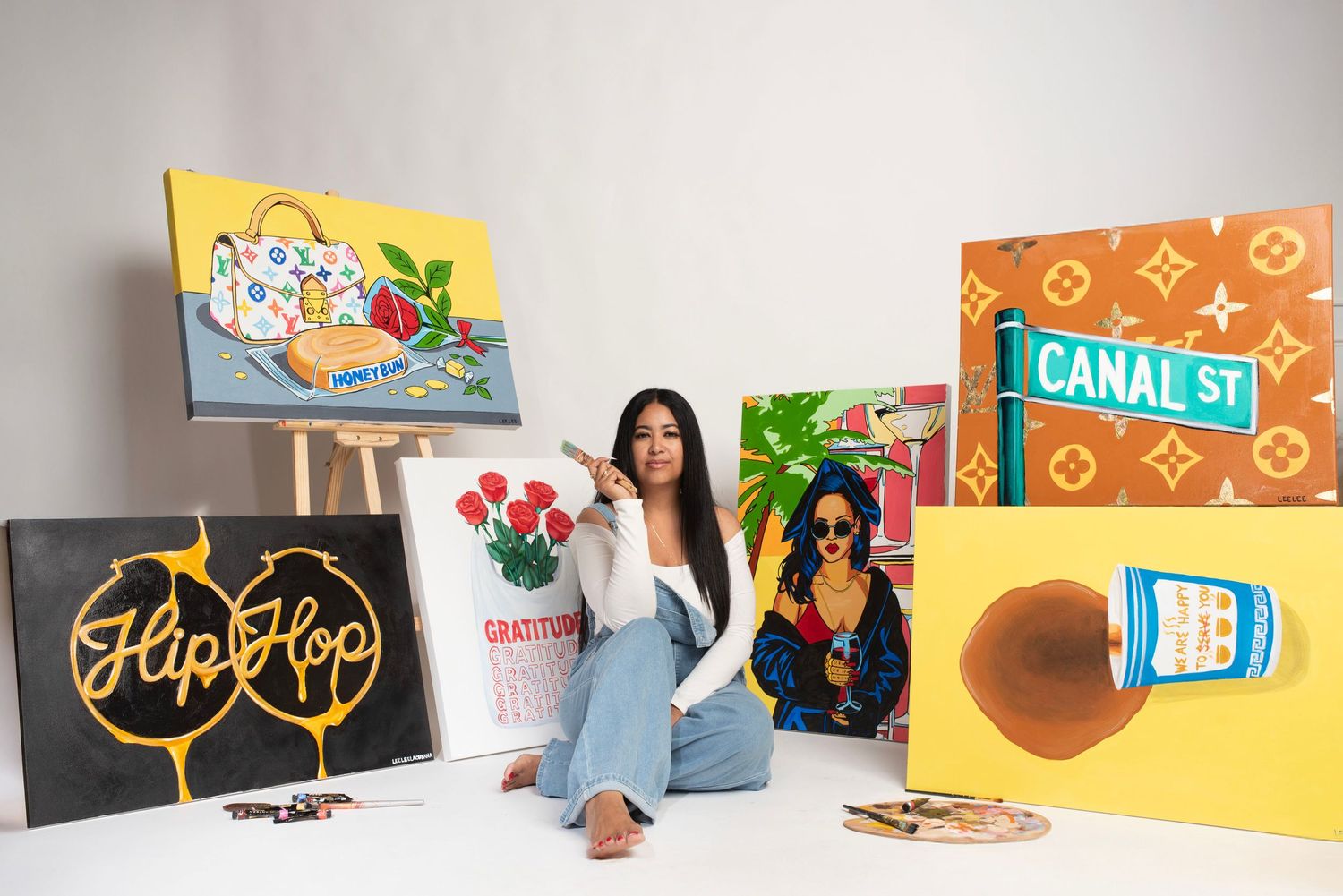 Lifestyle product photography setup with colorful props and signage against white background. Artist sitting with paintings