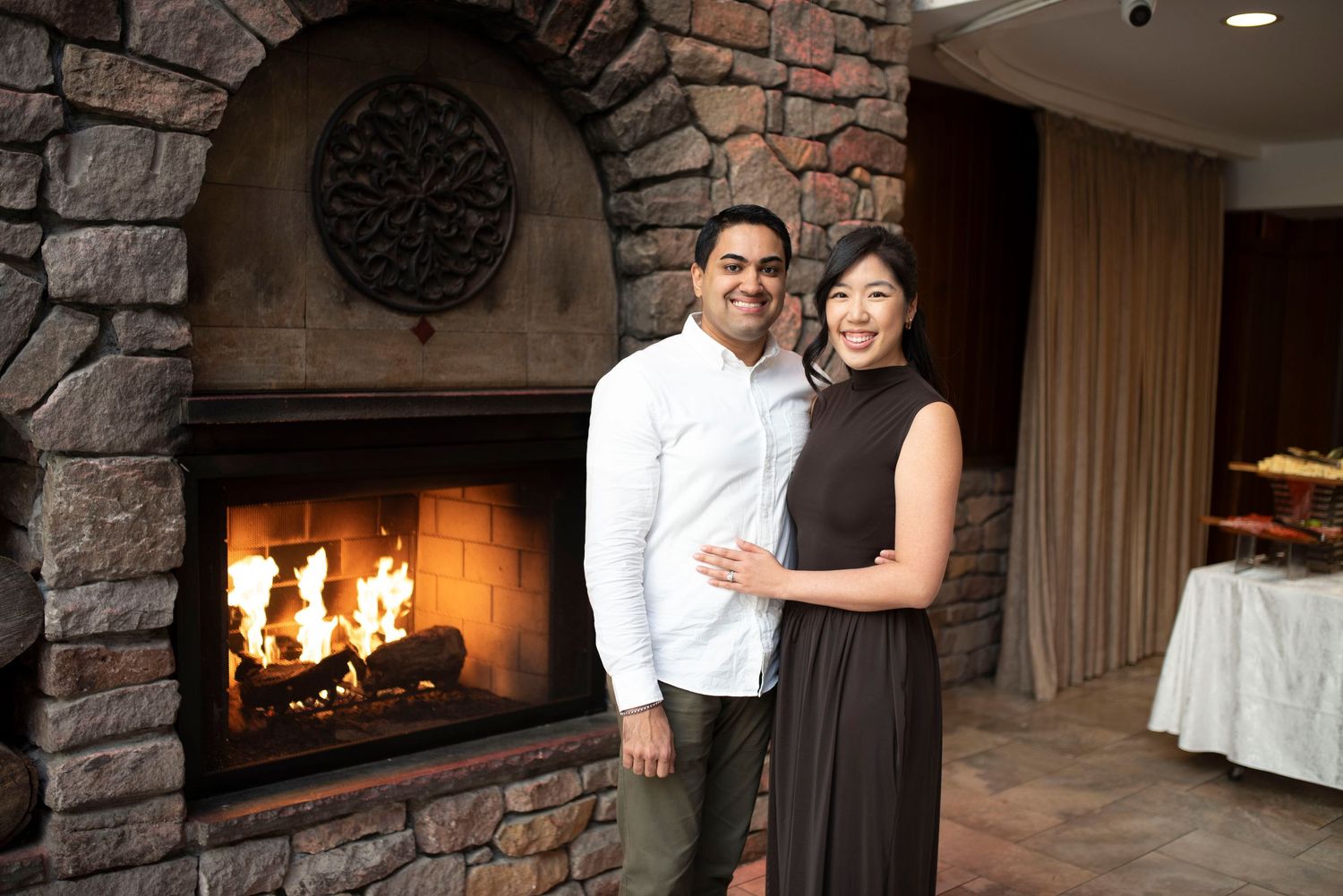 Couple smiling together in front of a stone fireplace in an elegant restaurant setting.