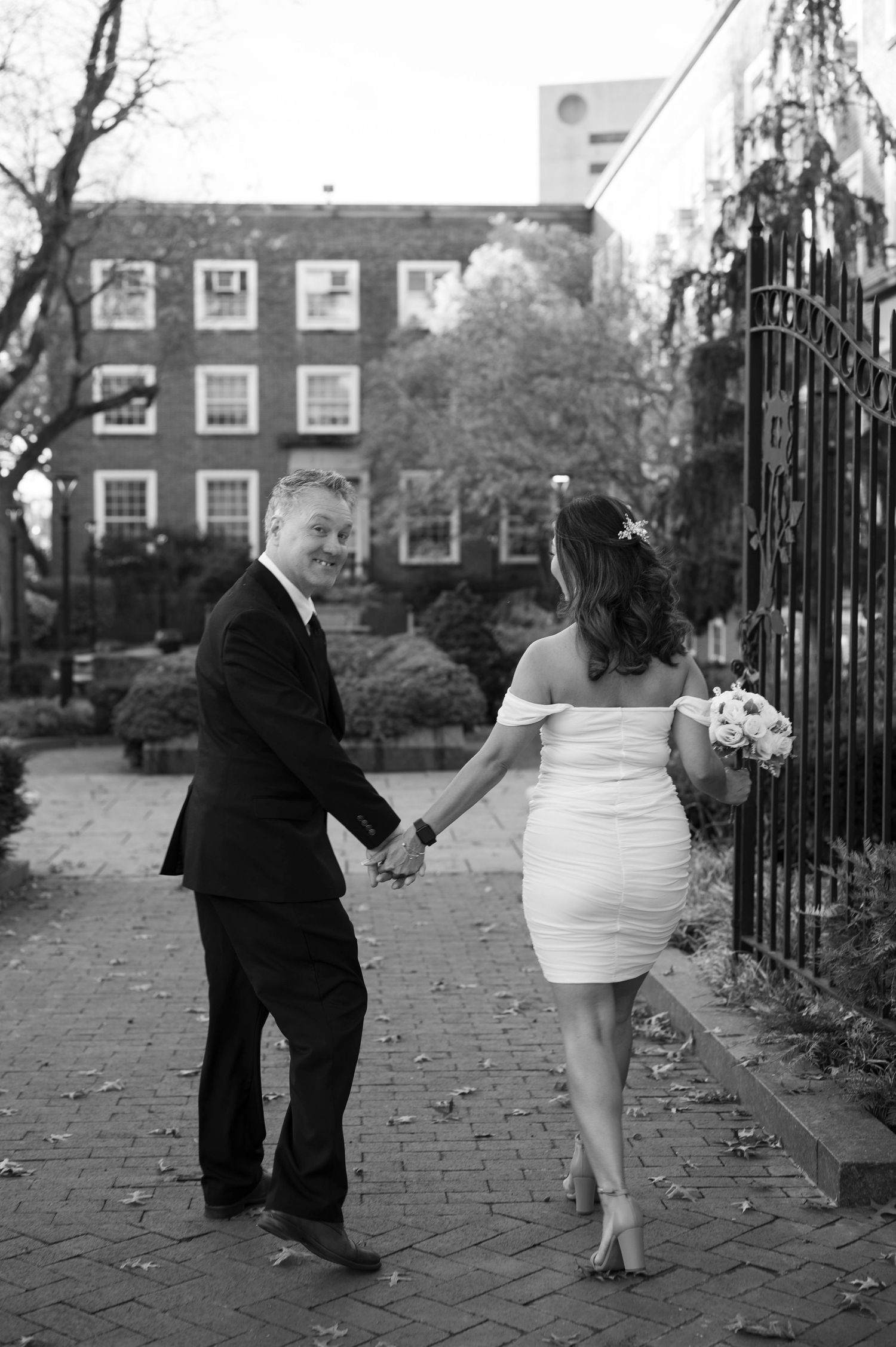 Couple walking together on a brick pathway near historic buildings.