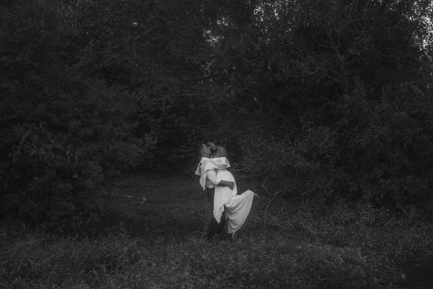 Engagement session, woman in white flowing dress being lifted into the air, black and white photo