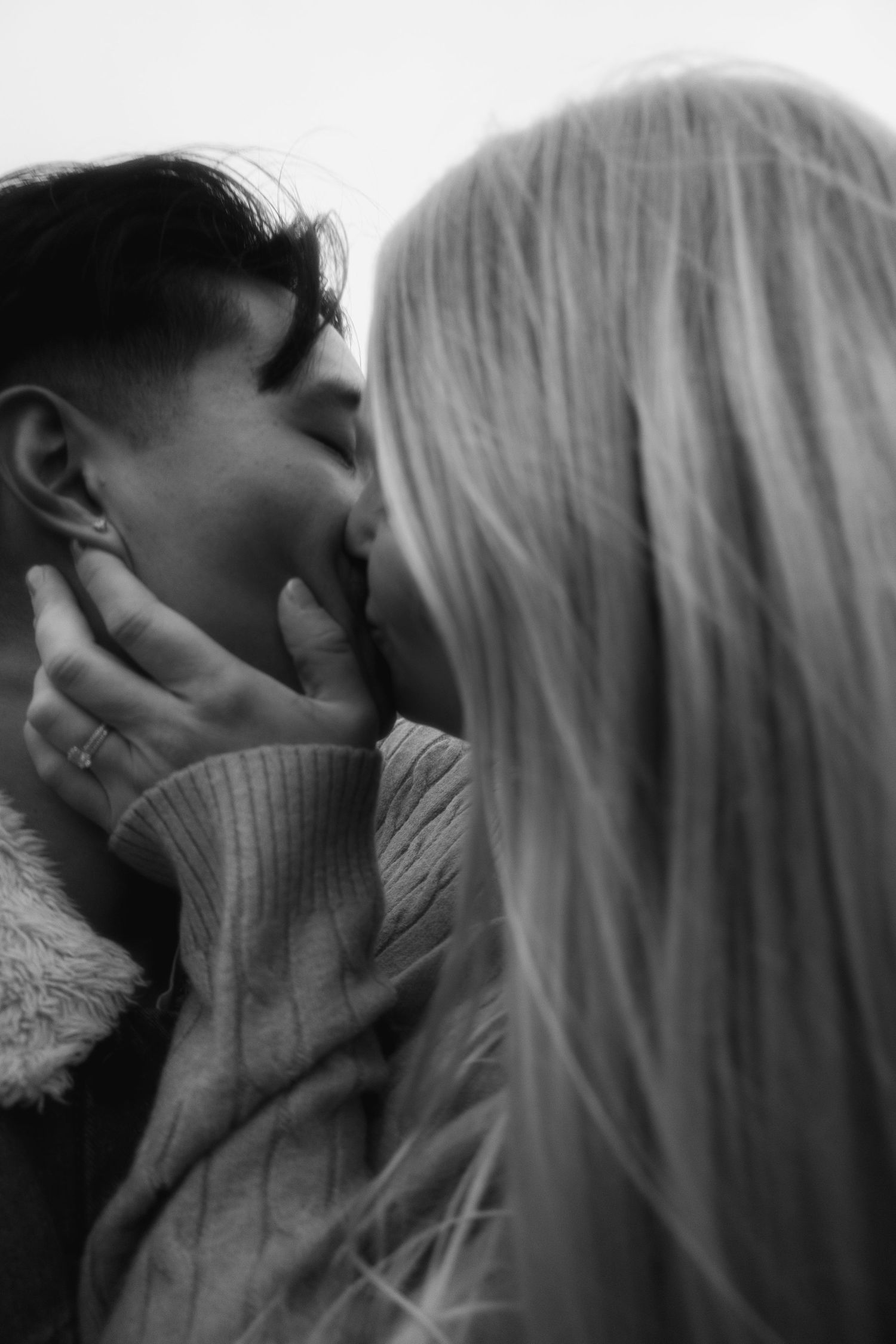 Black and white photography, editorial, cinematic style photography. Couple embracing, woman kissing her husbands cheek, grainy, film