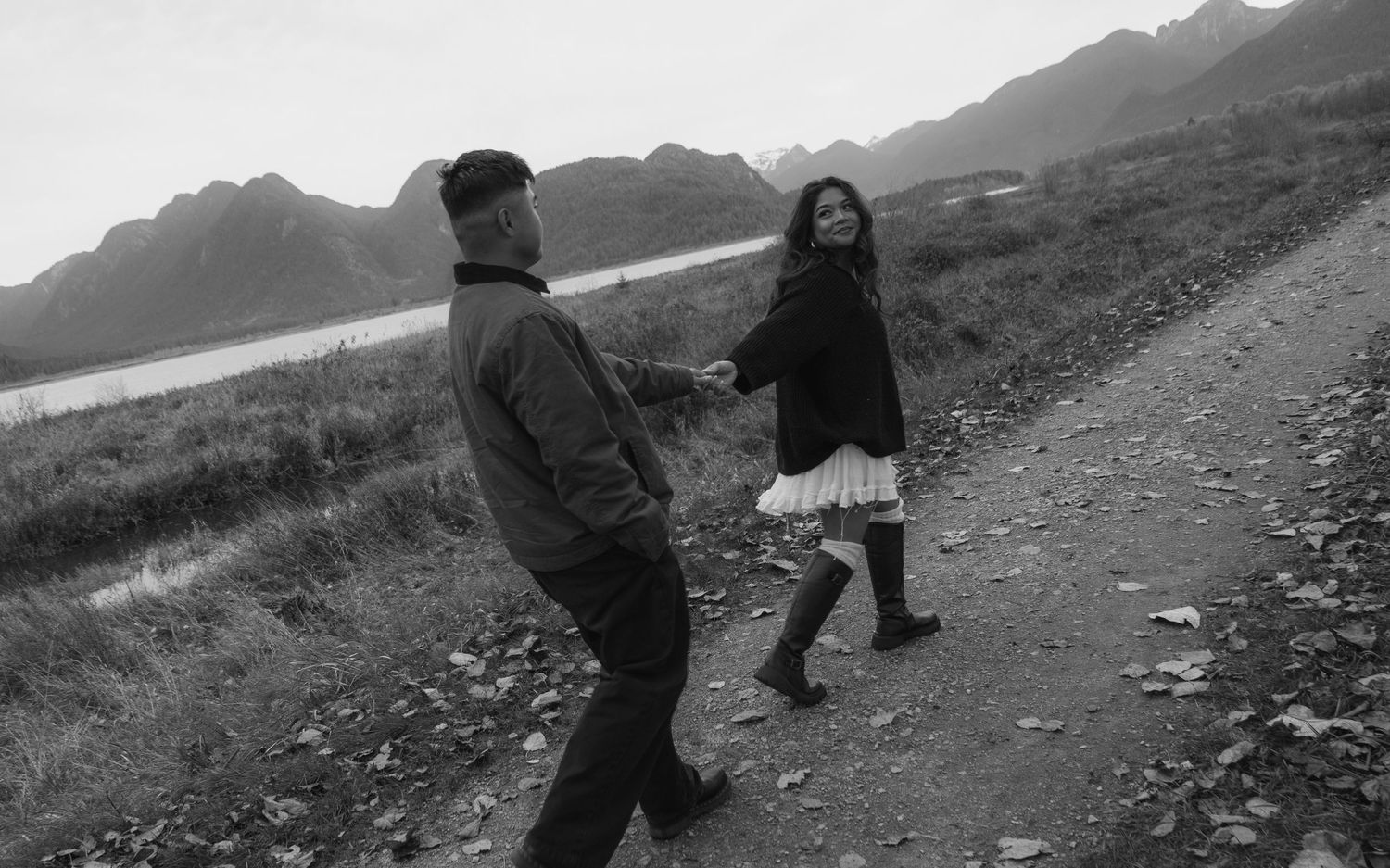 Black and white photo of a couple holding hands walking a trail. Intentional grain, film inspired, motion blurred.
