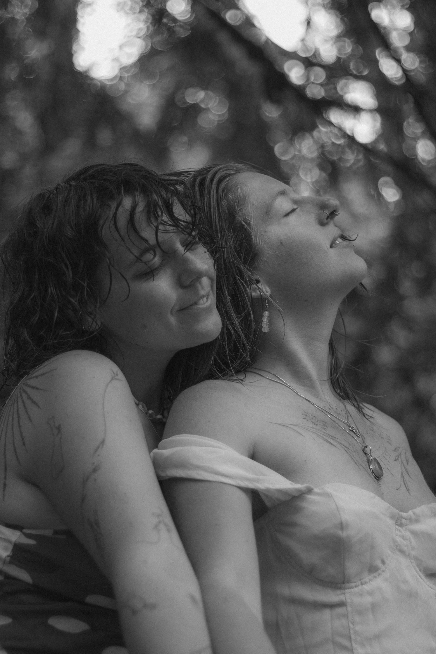 Black and white photo of couple in nature, one woman resting her head against the others. Soft, storytelling, cinematic style photographer