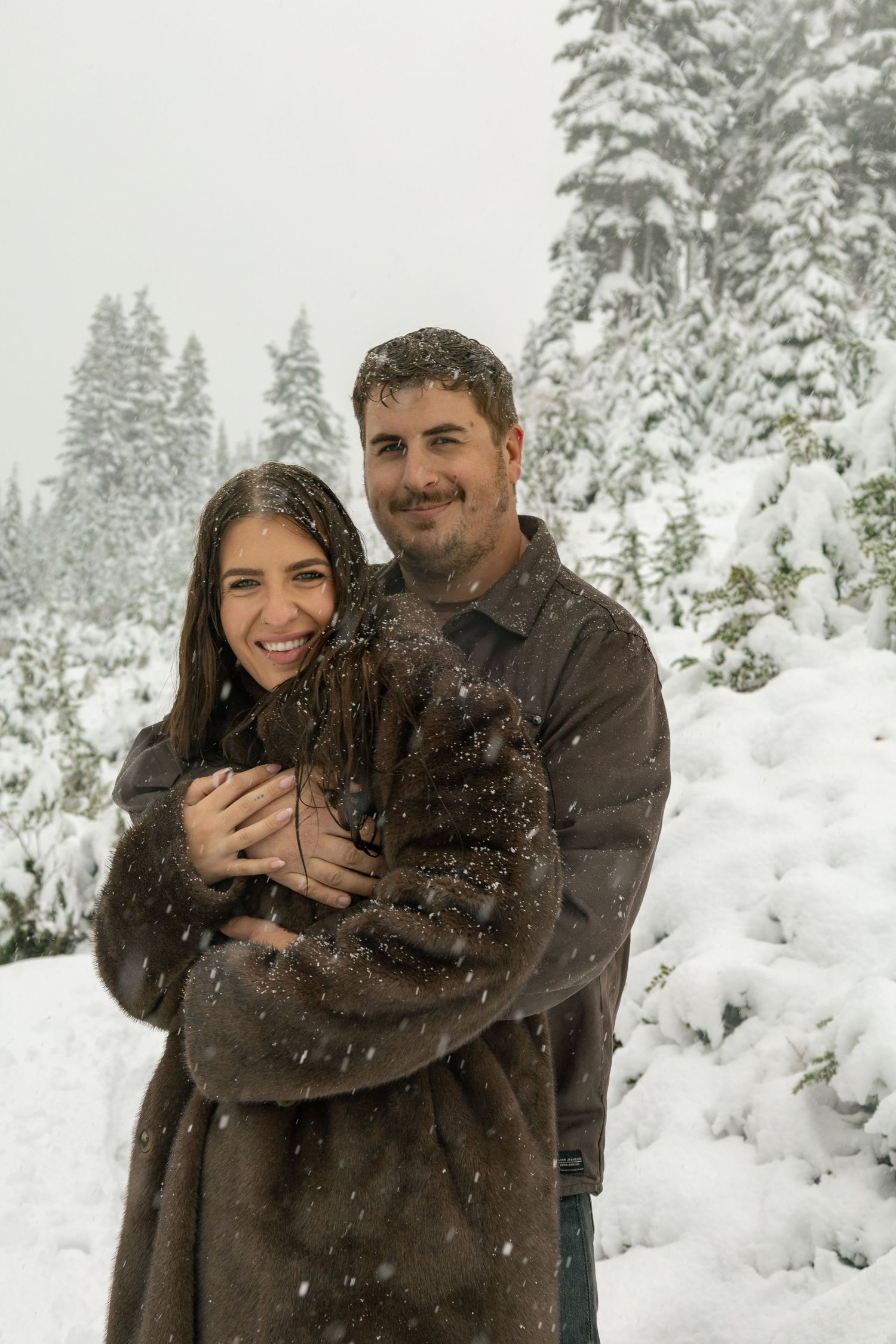 Photo of couple hugging, looking at camera, snowy background, documentary style photography