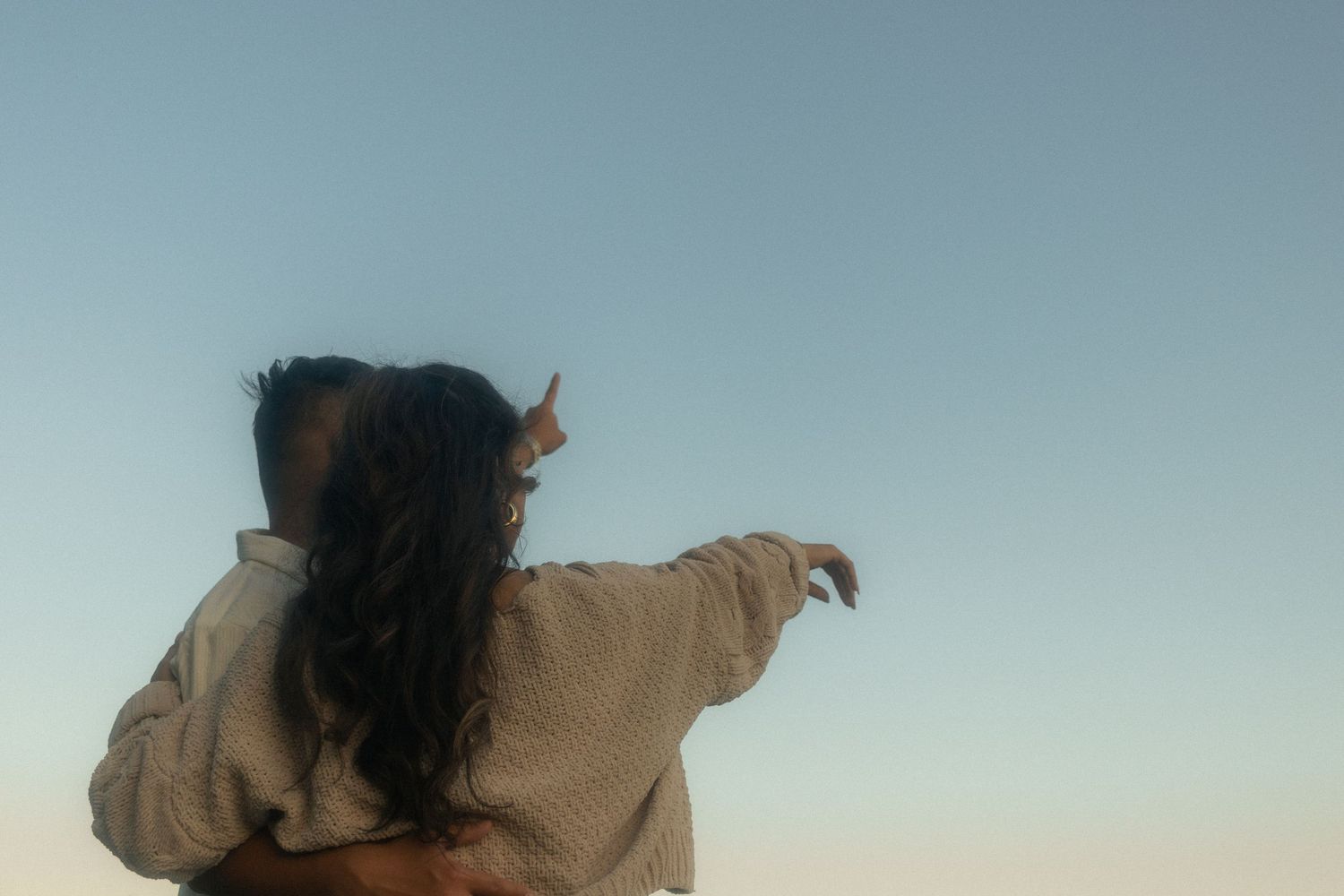Engagement session, couple at sunset pointing up into the sky