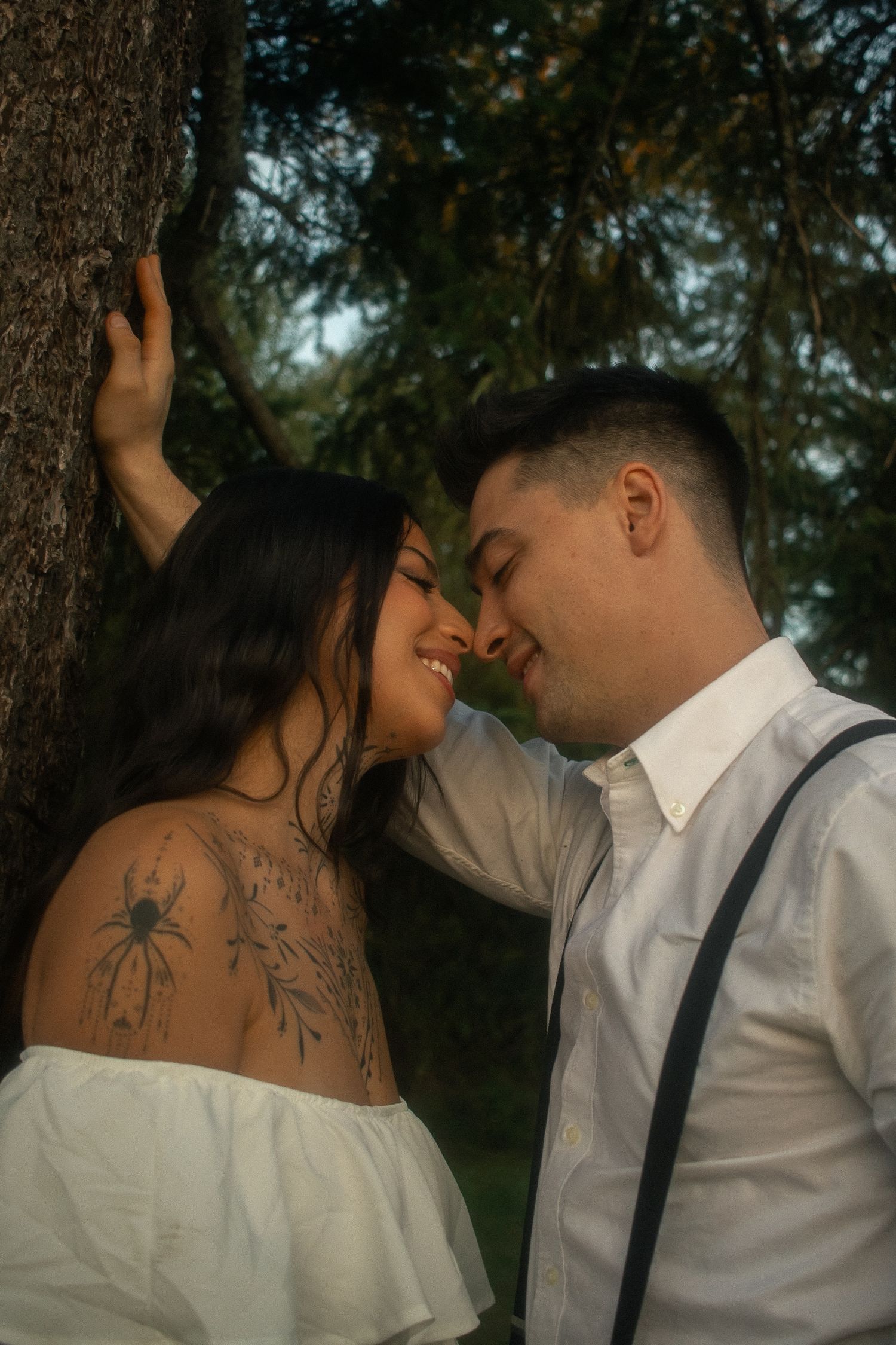 Engagement session, couple leaning against a tree