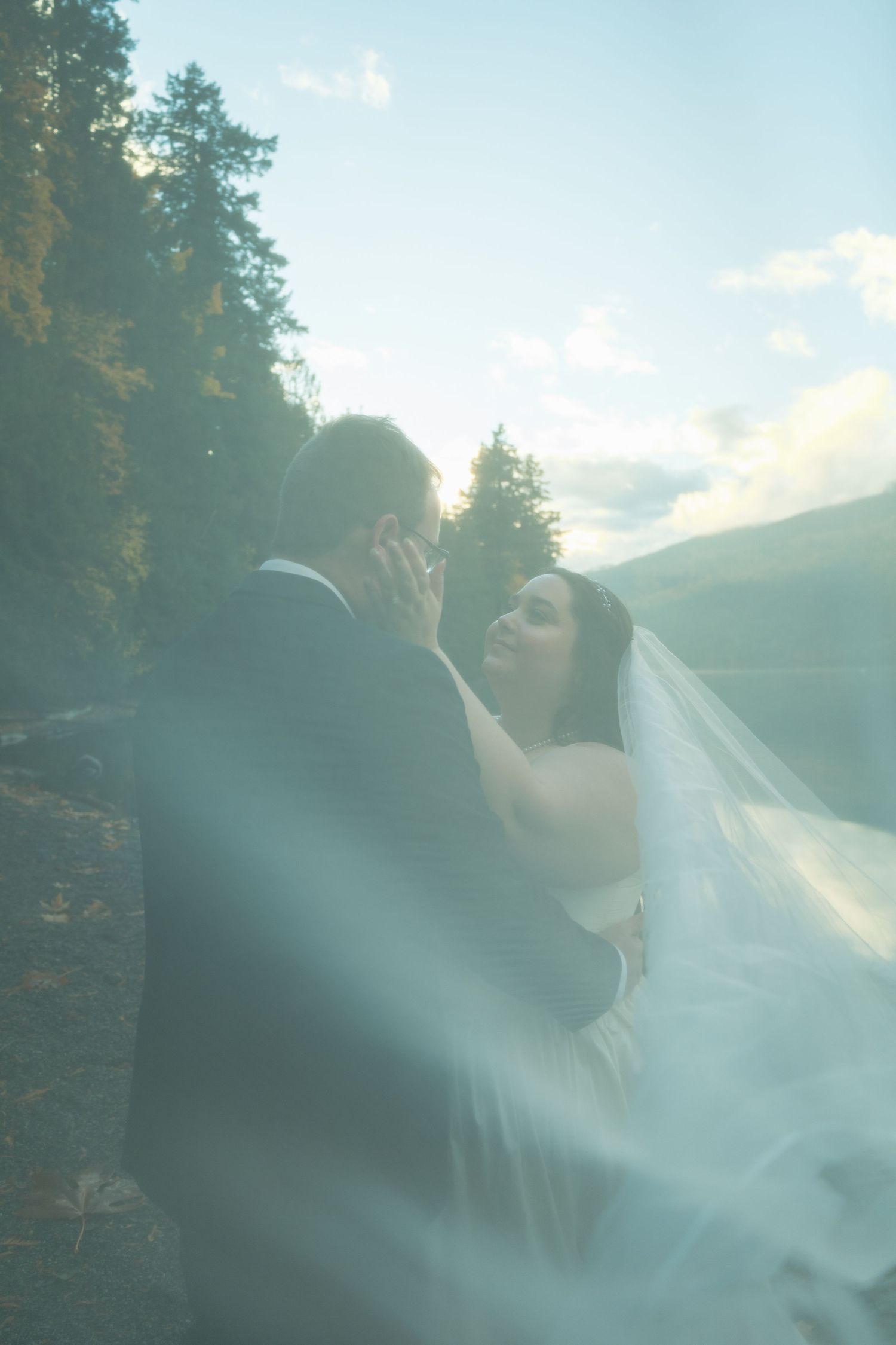 Photo of couple embracing, woman's veil is flowing towards the camera.